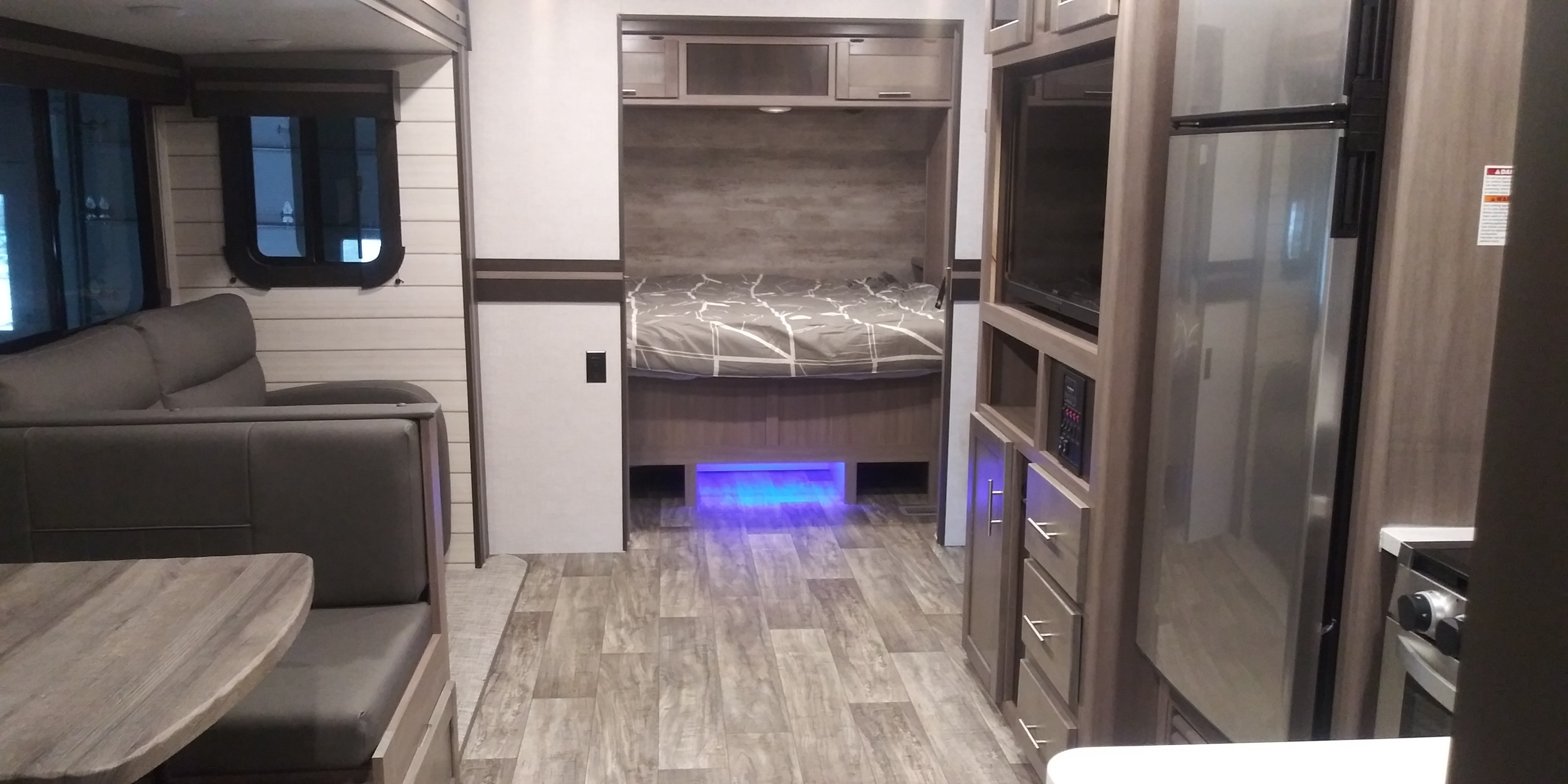 Spacious RV rental interior featuring a modern living area, cozy bunk bed with blue lights, and full kitchen.. 2022 Sunset Trail 2022