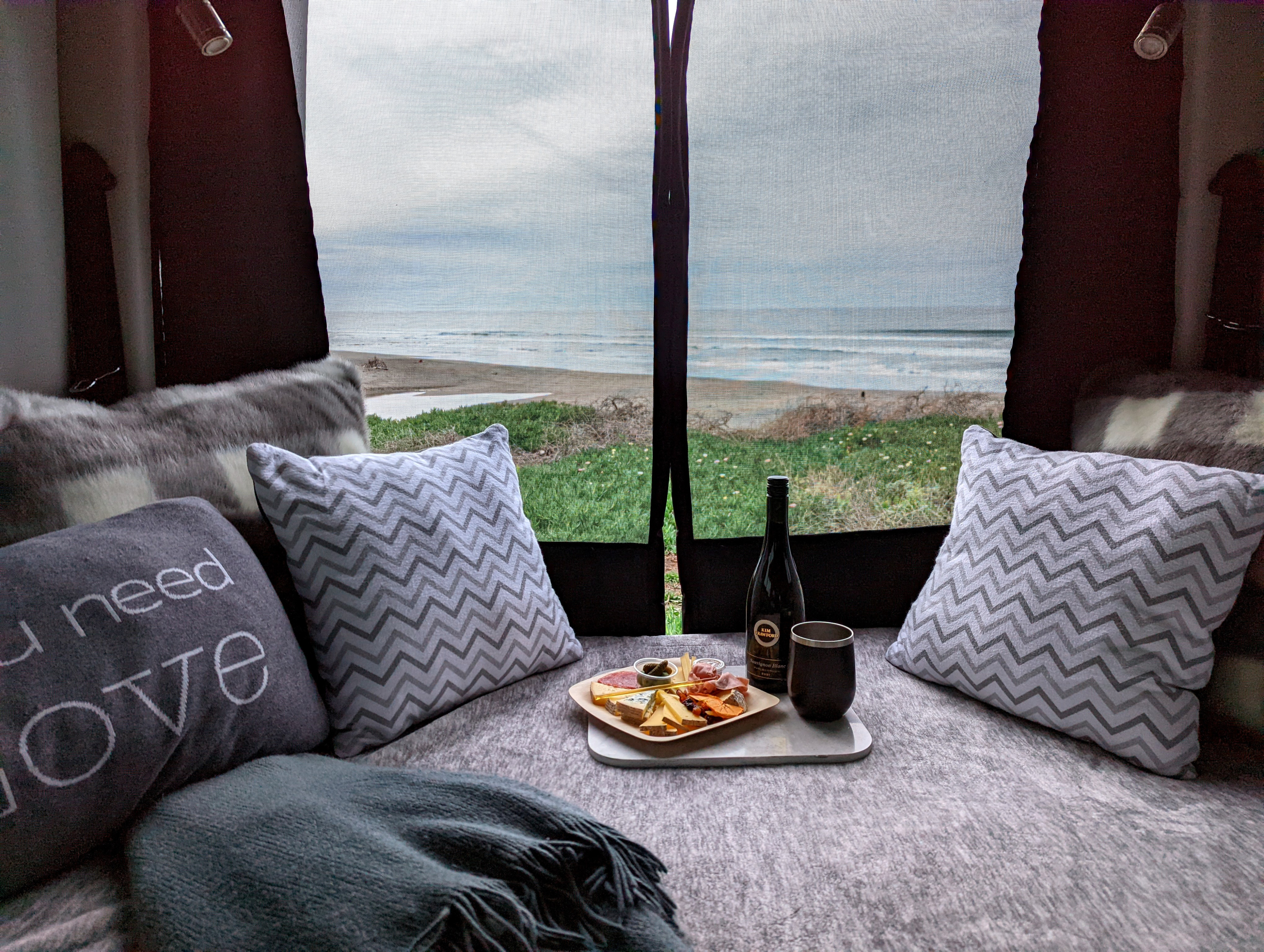 Cozy RV rental with ocean view: wine, charcuterie board, and plush pillows make for a perfect beachside retreat.. Thor Sanctuary 2022