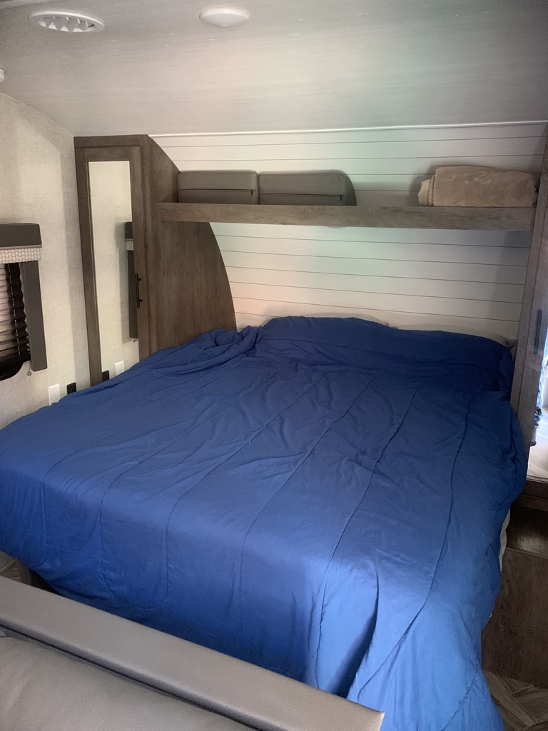 Spacious RV rental bedroom with a comfy blue bed, overhead storage, and light wood accents. Perfect for your next adventure.. Forest River Salem Cruise Lite 2021