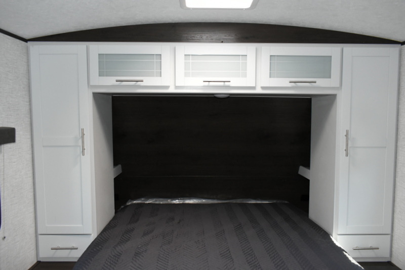 RV rental bedroom interior: Features a bed, modern white cabinets, and wardrobes with ample storage.. Keystone Bullet 290 BHS 2021