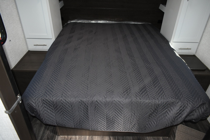 RV rental interior featuring a quilted bed flanked by built-in storage cabinets and nightstands. Ideal for road trips.. Keystone Bullet 290 BHS 2021