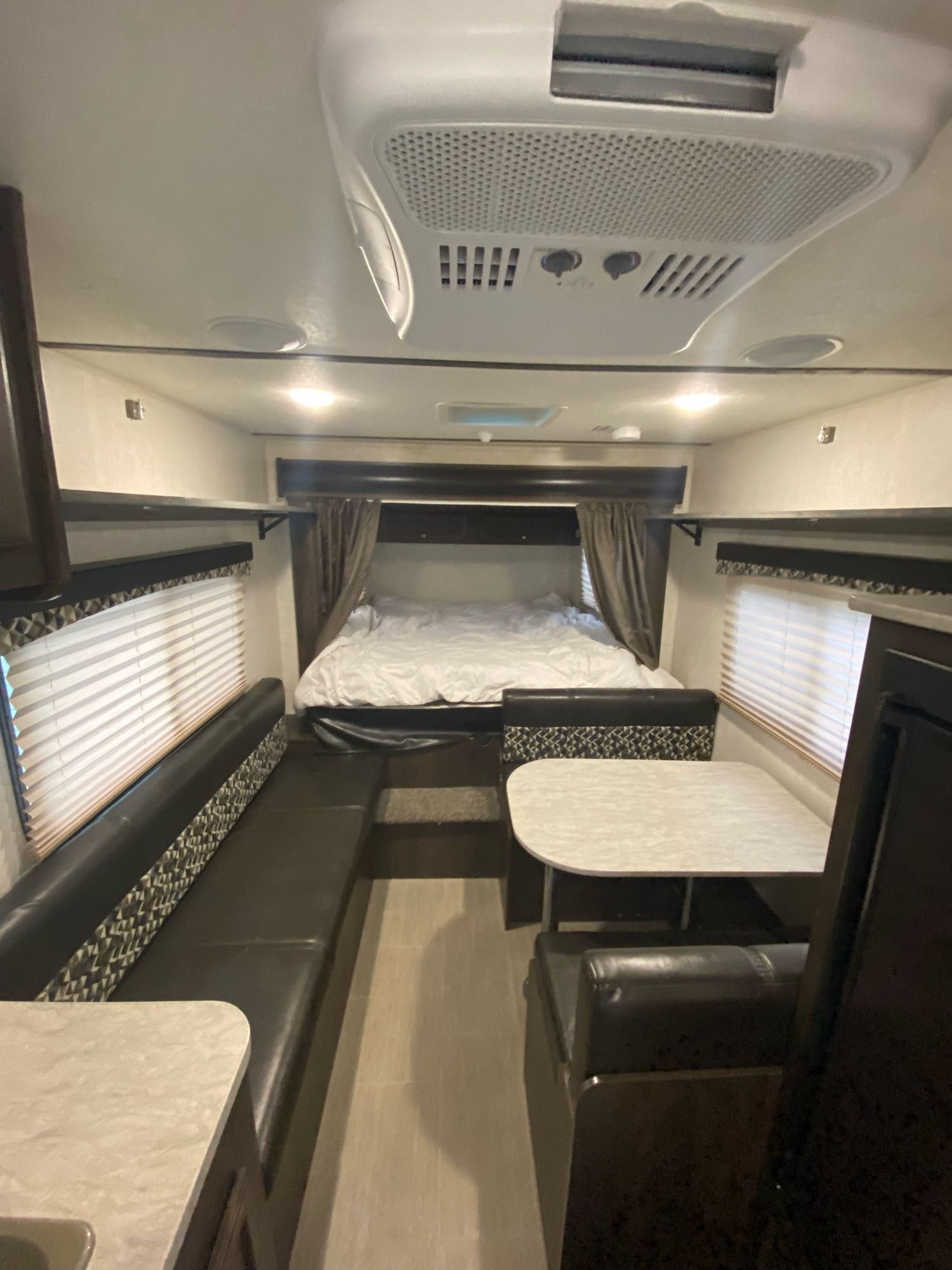 View of an RV rental's interior, showing a bed, dinette, windows, and overhead storage, designed for comfortable travel.. Starcraft Launch Outfitter 2018