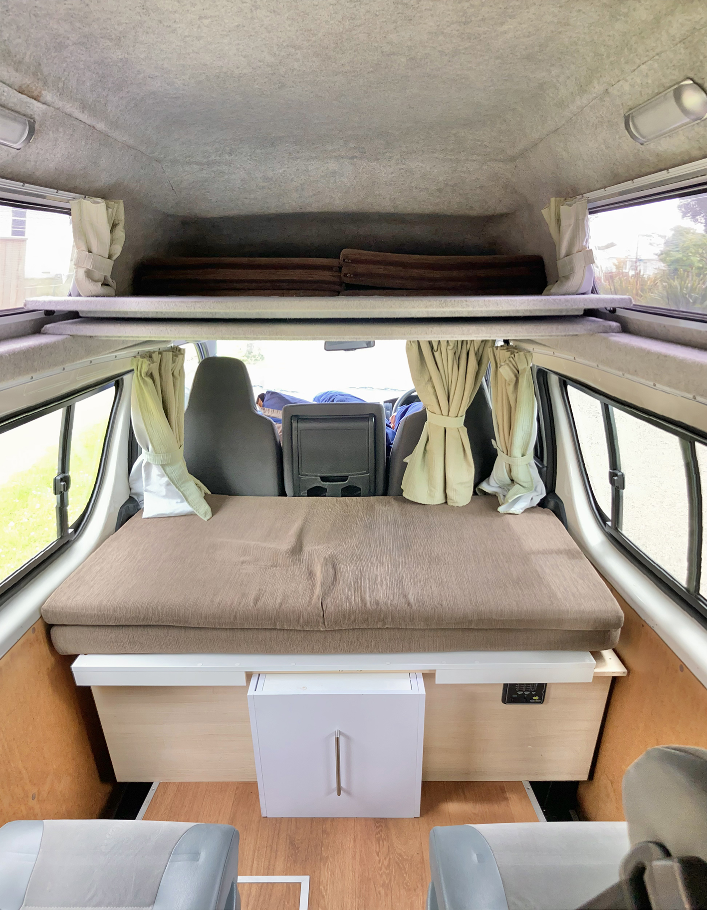 RV rental interior shows a lower bed, upper bunk, and built-in storage, perfect for your mobile adventures.. Toyota Hiace 2013