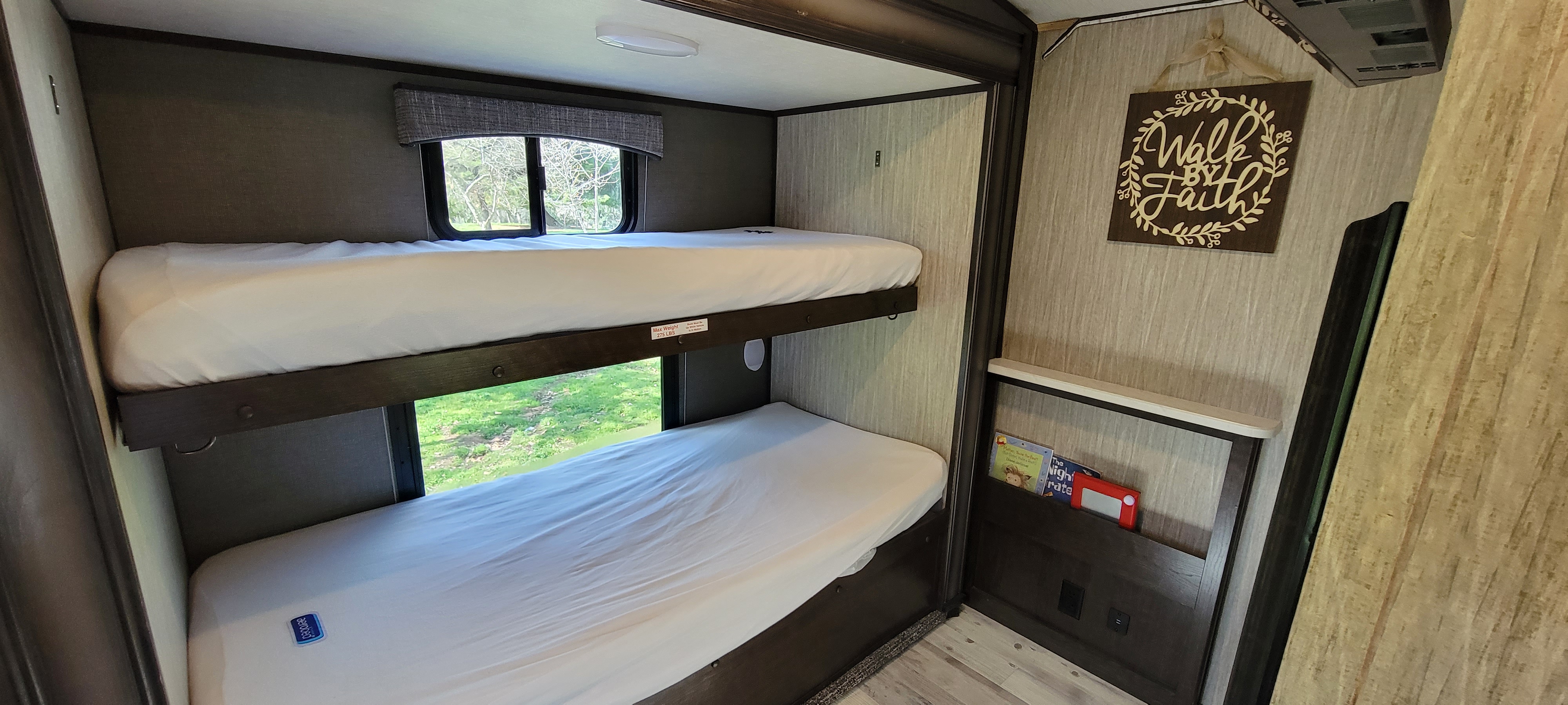 Cozy RV rental interior featuring twin bunk beds, crisp white sheets, and a window with nature views.. Heartland RVs Sundance 2018