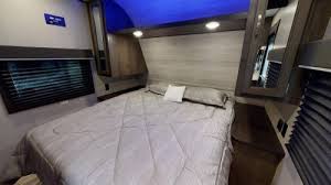 Spacious RV rental bedroom with a queen bed, window blinds, overhead cabinets, and soft blue accent lighting for travel.. Jayco Jay Flight SLX 2021