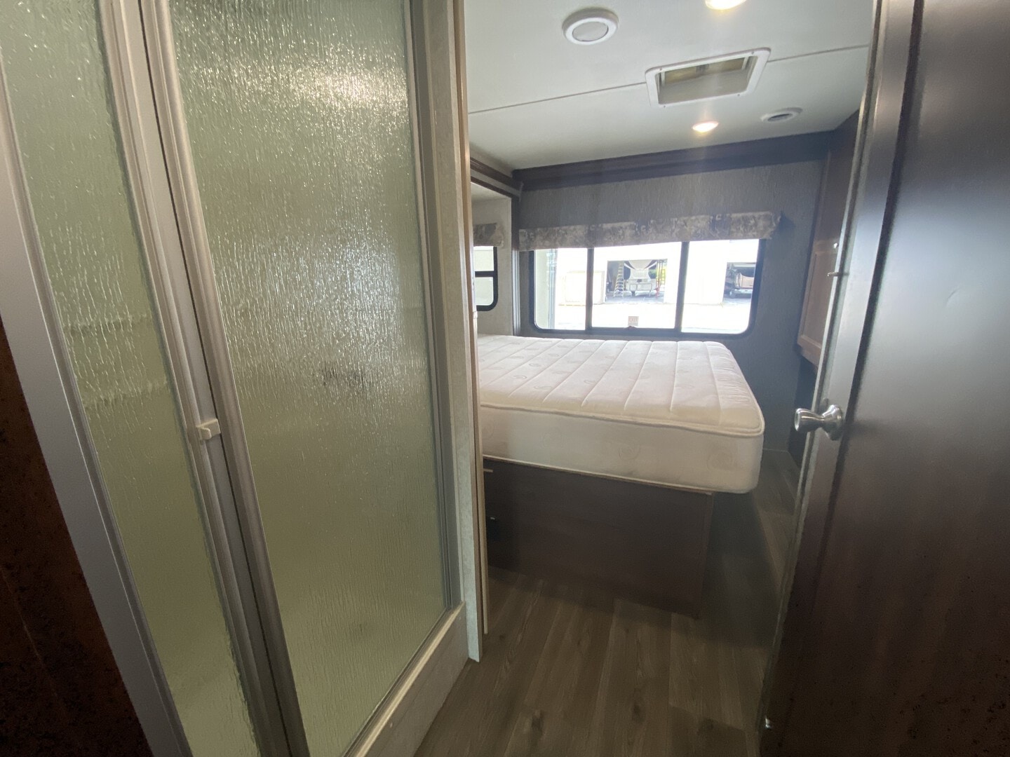 This RV rental's bedroom interior features a white mattress, window with outdoor view, and a frosted glass shower on the left.. Forester Forester Motorhome 2017