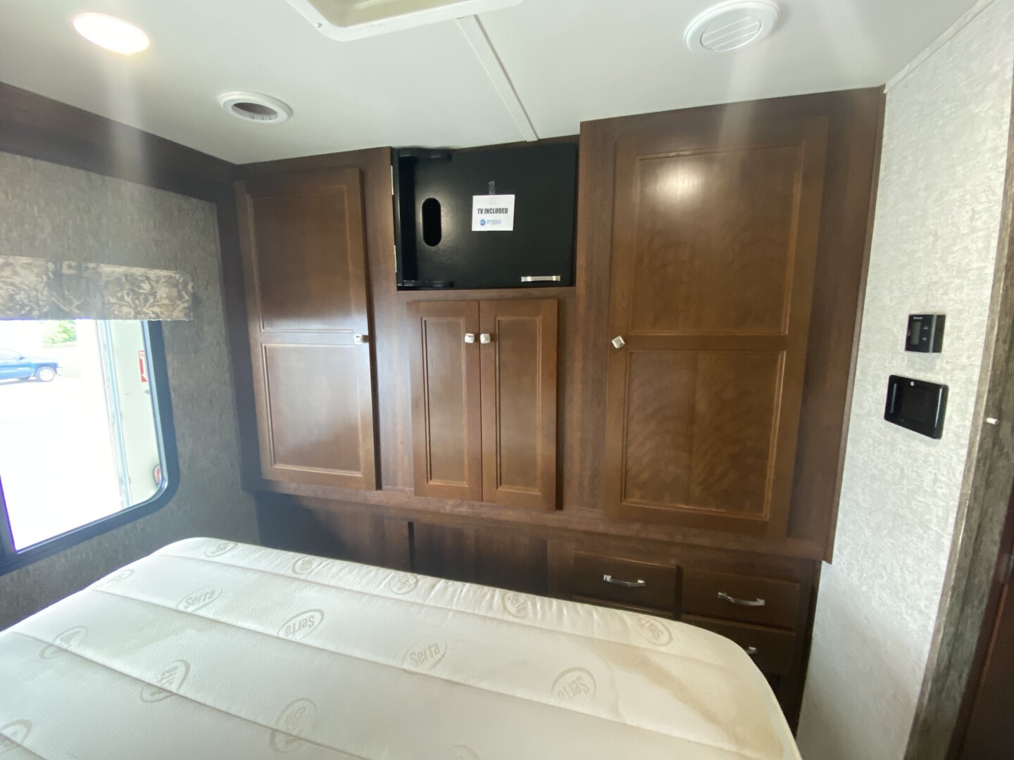 Spacious RV rental bedroom with Serta mattress, built-in wooden cabinets, and TV mount, offering comfortable travel.. Forester Forester Motorhome 2017
