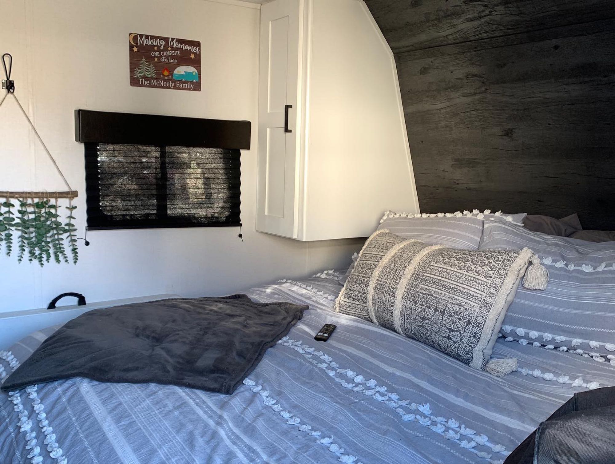 Inviting RV rental bedroom features striped bedding, decorative pillows, a dark wood wall, and a custom "Making Memories" sign.. Other Hideout 2021