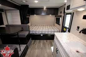 This RV rental interior shows a compact living space with kitchen, dining booth, and bed, ideal for travel and camping.. Jayco Jayco 184Bs 2022
