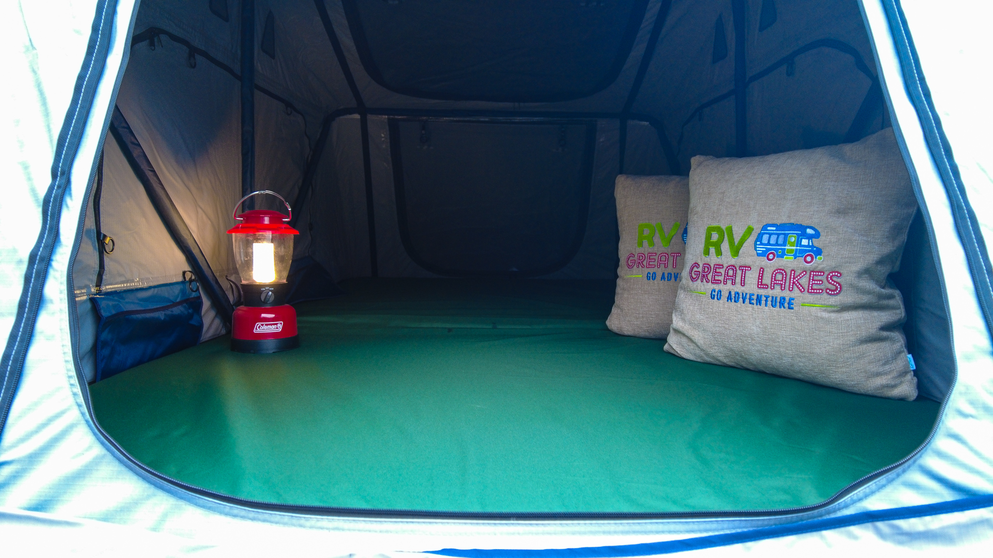 Inside an RV rental tent: a Coleman lantern, comfy green bed, and "RV Great Lakes" pillows await your adventure.. Subaru Forester XT 2017