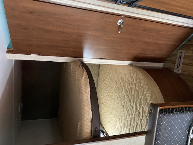 Inside an RV rental: an open storage compartment reveals cushions for a versatile sleeping area.. prowler lynx 22LX 2015