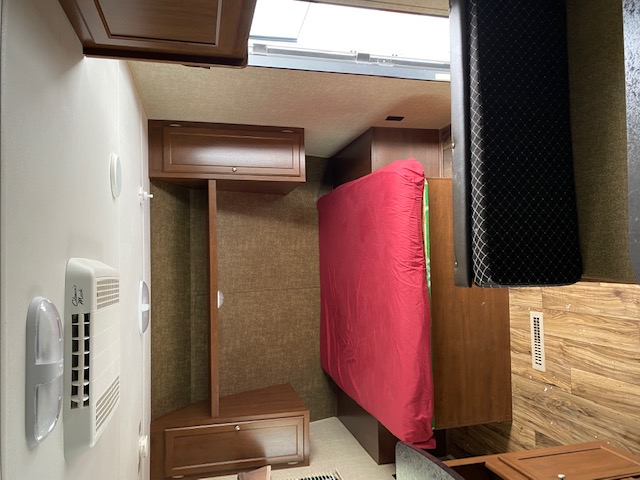 RV rental interior showcasing a sleeping area with red bed, ample storage, and wall amenities for comfort.. prowler lynx 22LX 2015