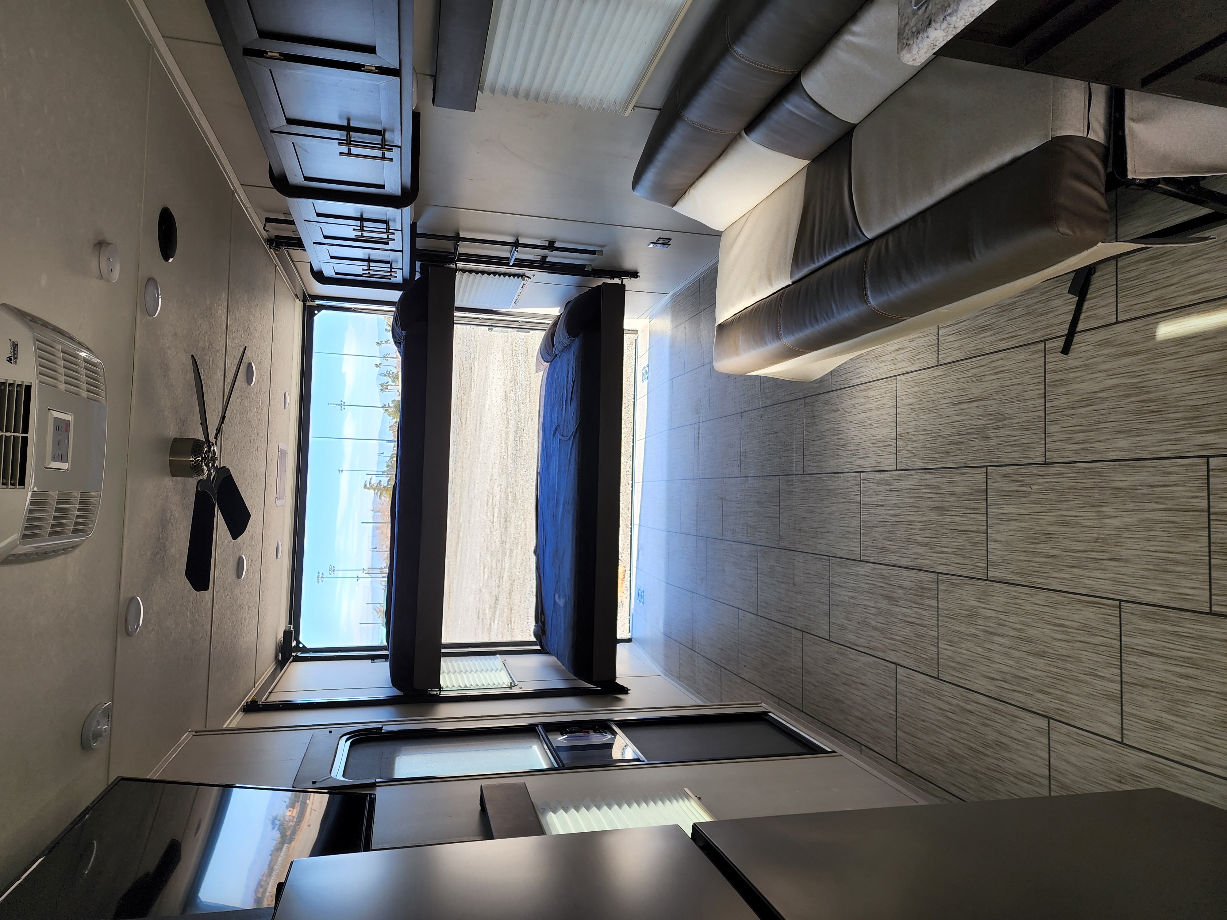 Spacious RV rental interior: living area with sofa, modern kitchen, ceiling fan, and rear ramp with convertible bunk beds.. Man Cave TH28 2022