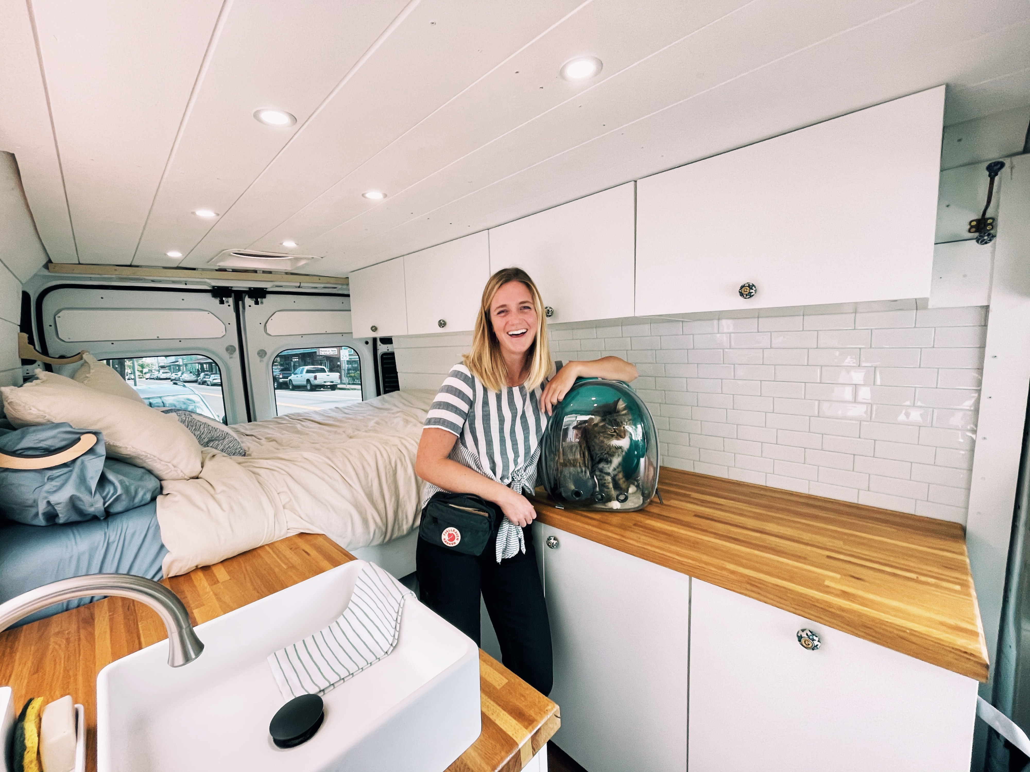 Happy woman & cat in a cozy, modern RV rental, featuring a bed, kitchen, and pet-friendly space.. Ram Promaster 2017