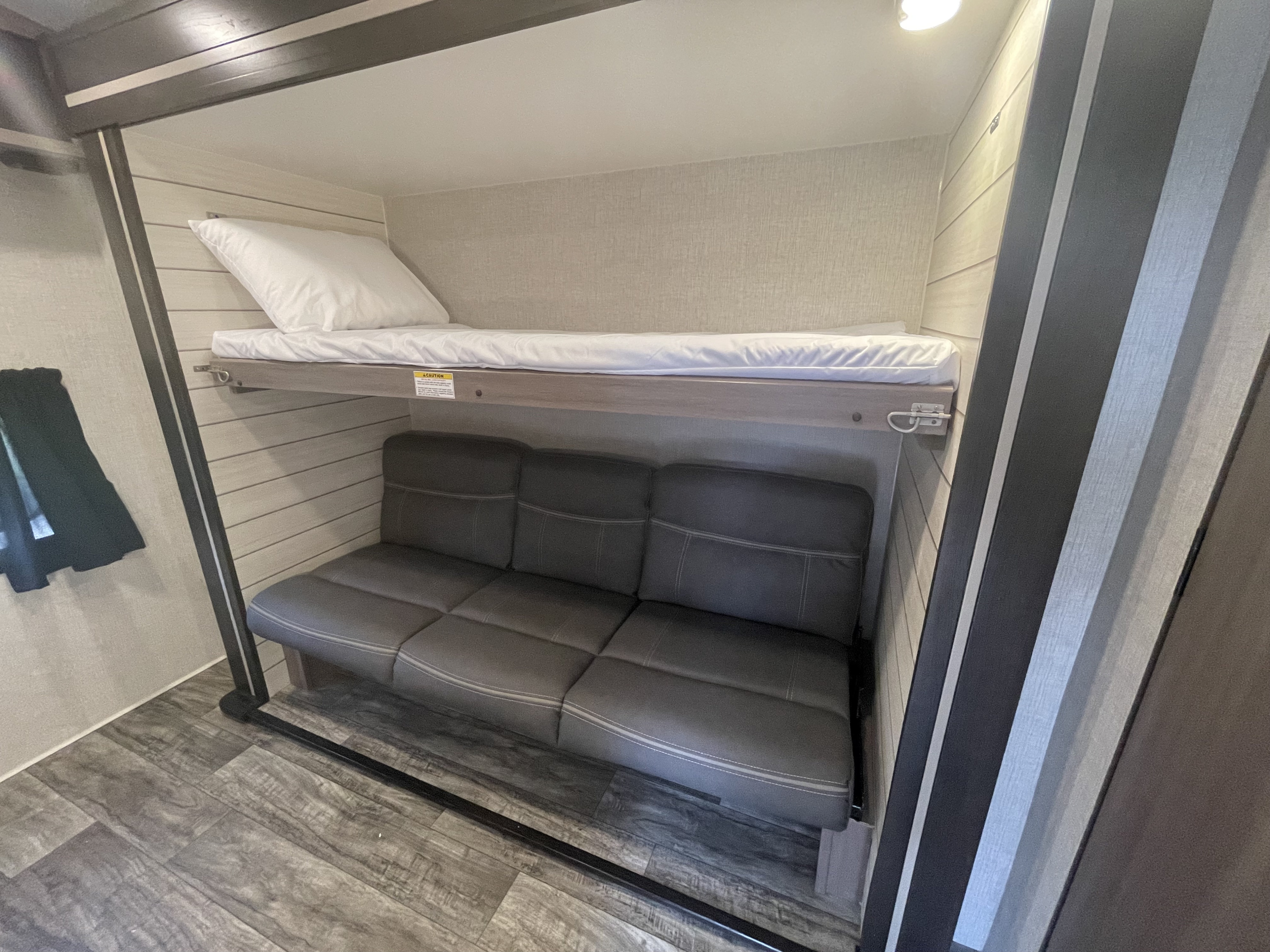 This RV rental showcases a cleverly designed bunk bed above a plush gray sofa, maximizing sleeping and living space.. Crossroads RV Sunset Trail 2022