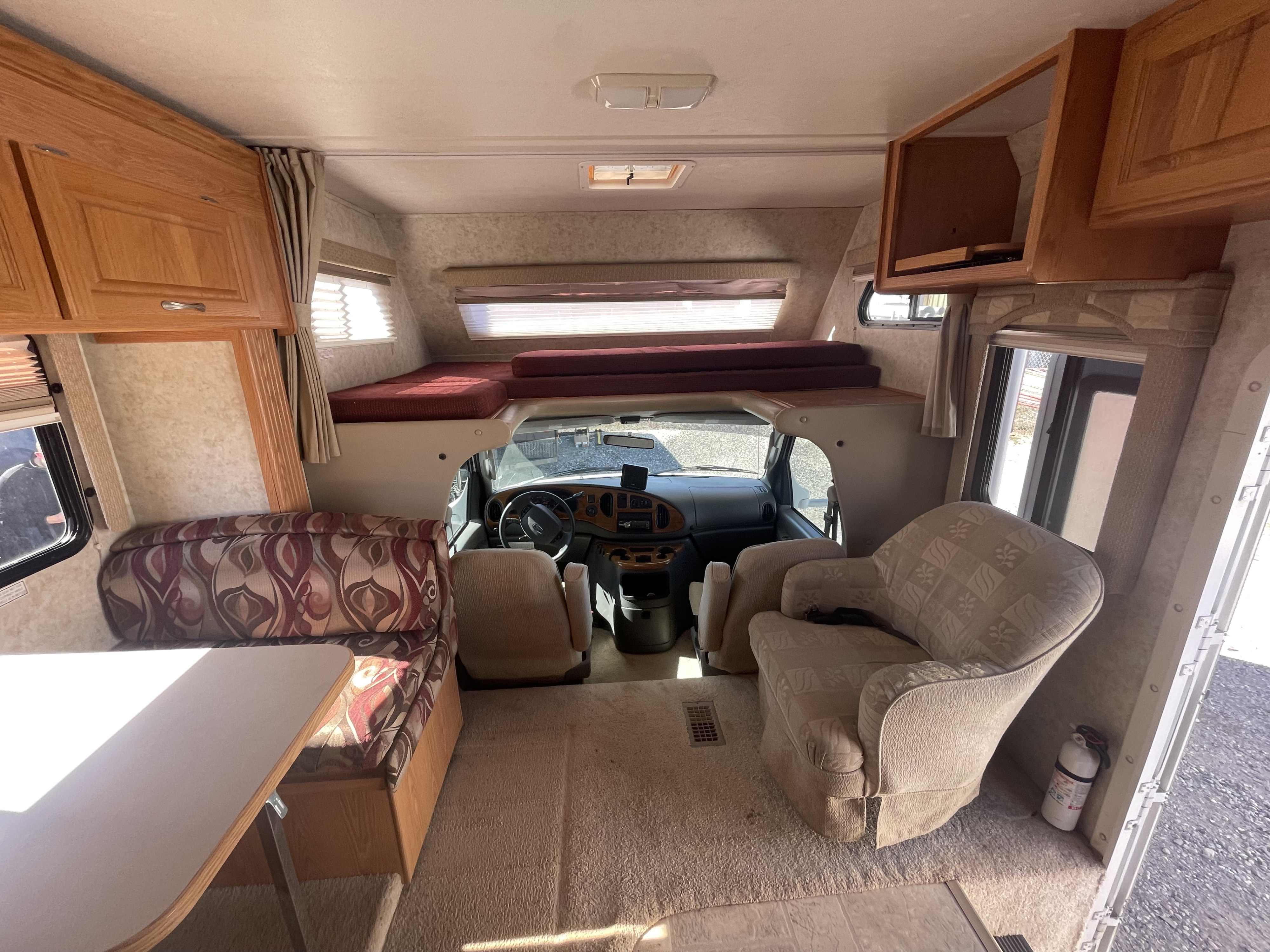 Inviting RV rental interior features a dinette, overhead bunk bed, and cozy recliner, offering a comfortable living space.. Ford Chateau Sport 2004