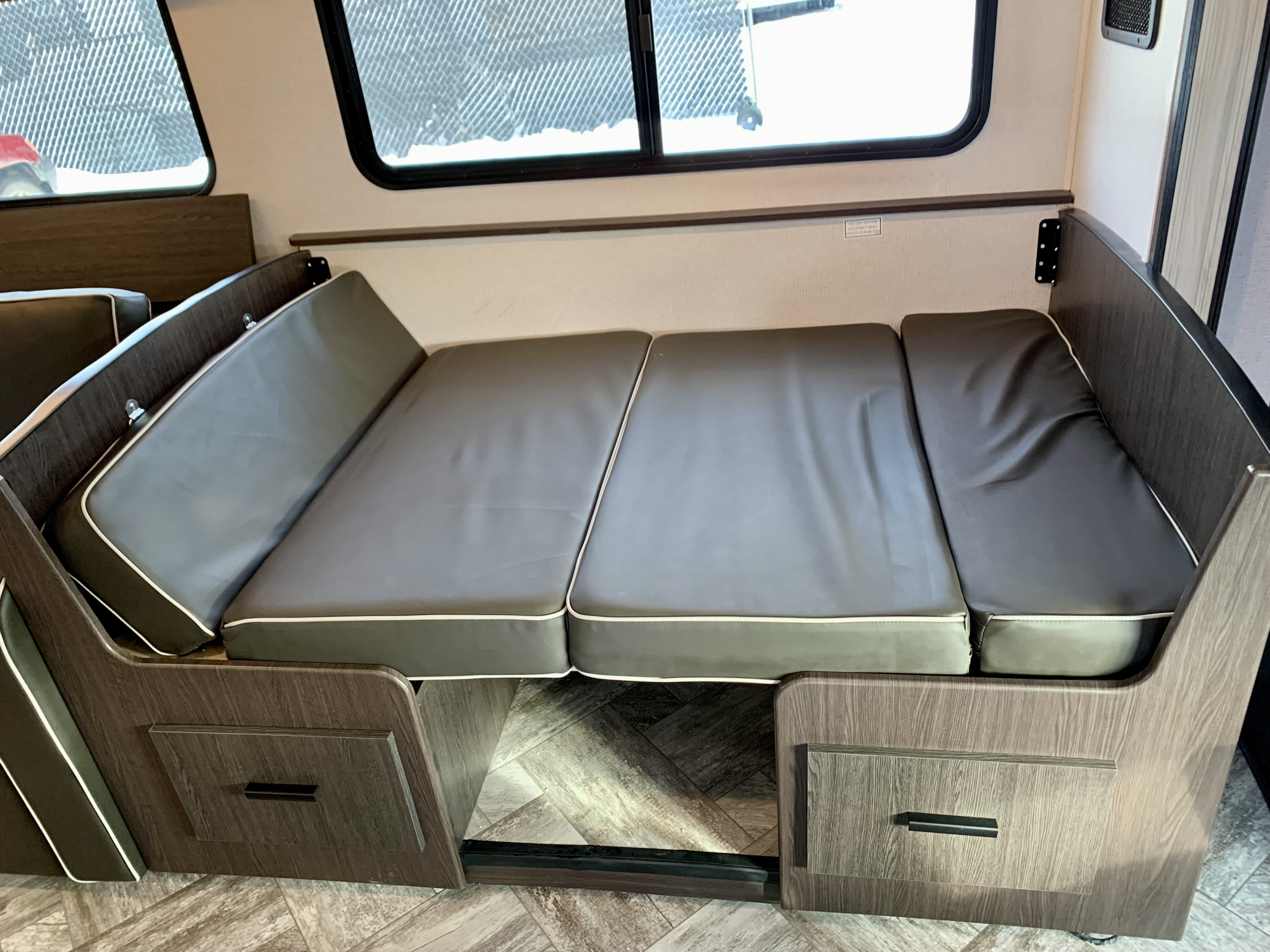 RV rental interior: Versatile dinette with dark cushions converts to a bed. Wood-look finishes and under-seat storage are visible.. Forest River Forester 2551DSLE 2021