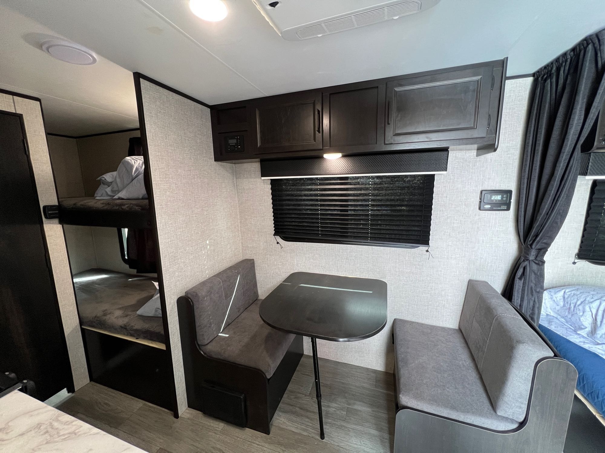 Cozy RV rental interior featuring comfortable bunk beds, a dinette, and overhead storage. Ideal for family travel.. Jayco Jay Flight 2022