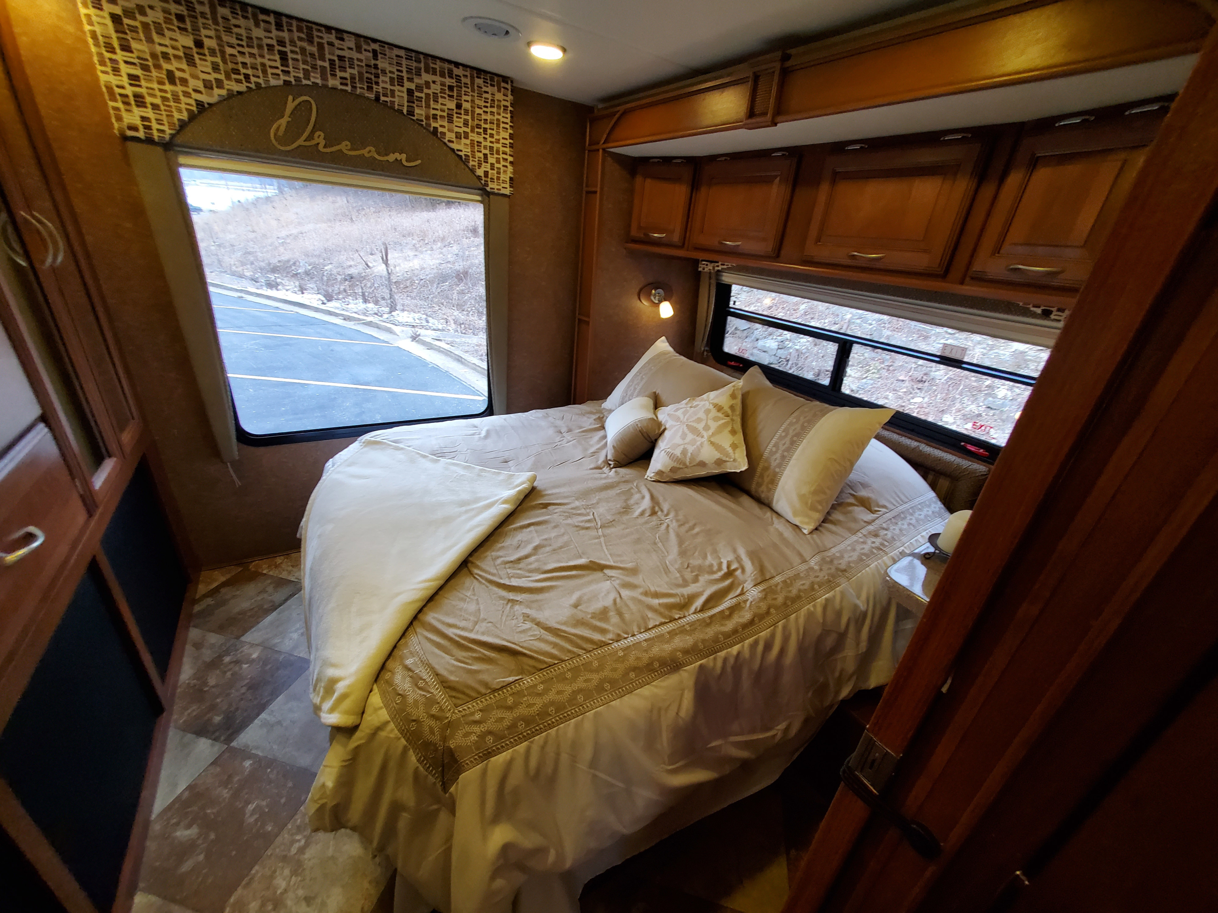 Cozy RV rental bedroom with a comfortable bed, wood cabinets, and large windows. Perfect for your travel dreams.. Forest River Coachmen Concord 2014