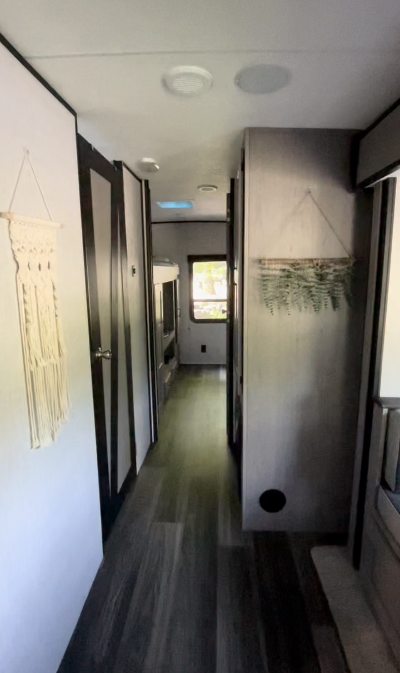 RV rental: Interior hallway with white walls, dark trim, and wood-look floor. Macrame art & plant decor visible. Leads to bunk area.. Heartland RVs Mallard 2021
