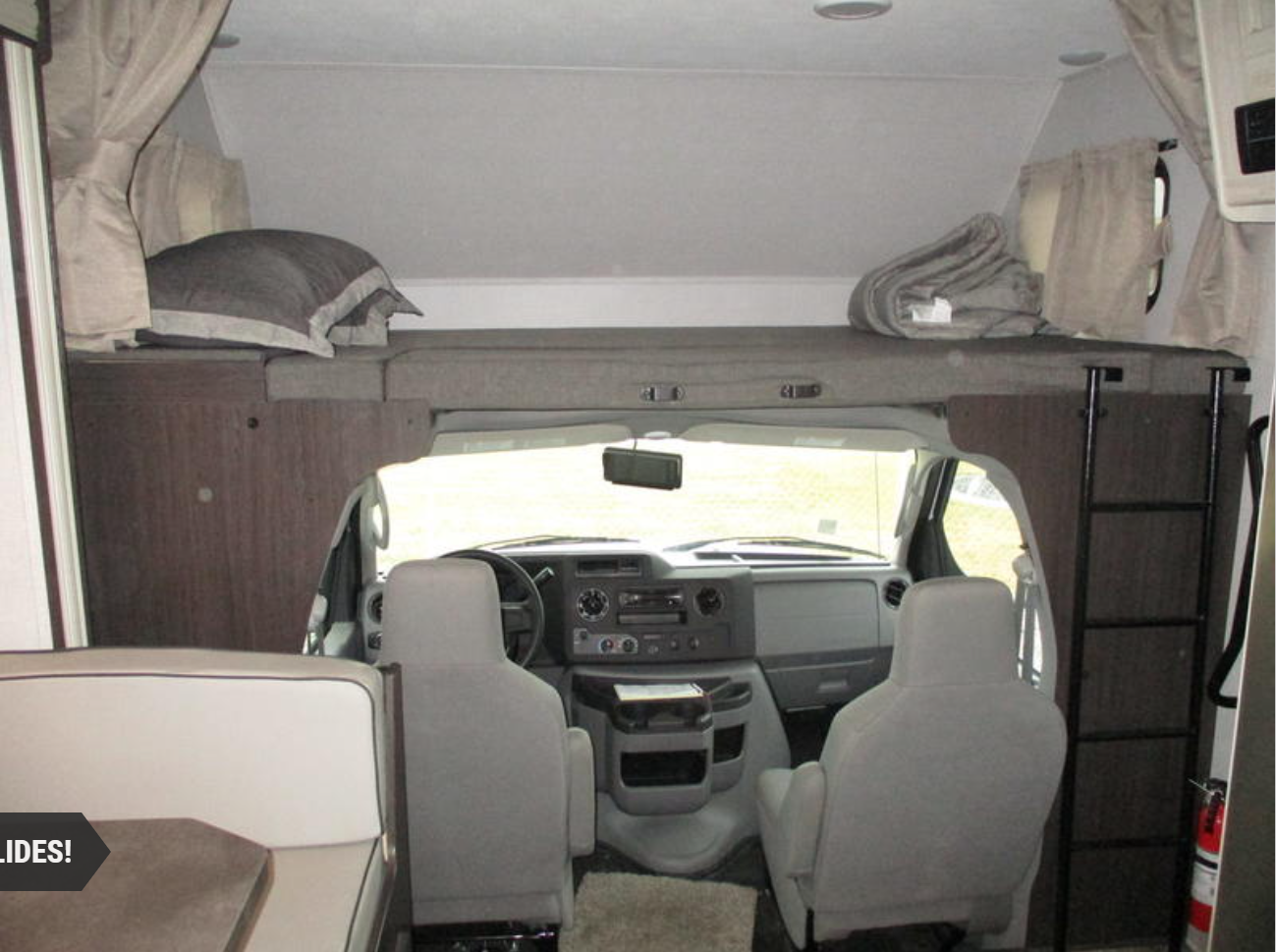 Inside an RV rental: View of the front cab, overhead bunk with pillow, and a ladder for access.. Forest River Sunseeker LE 2021