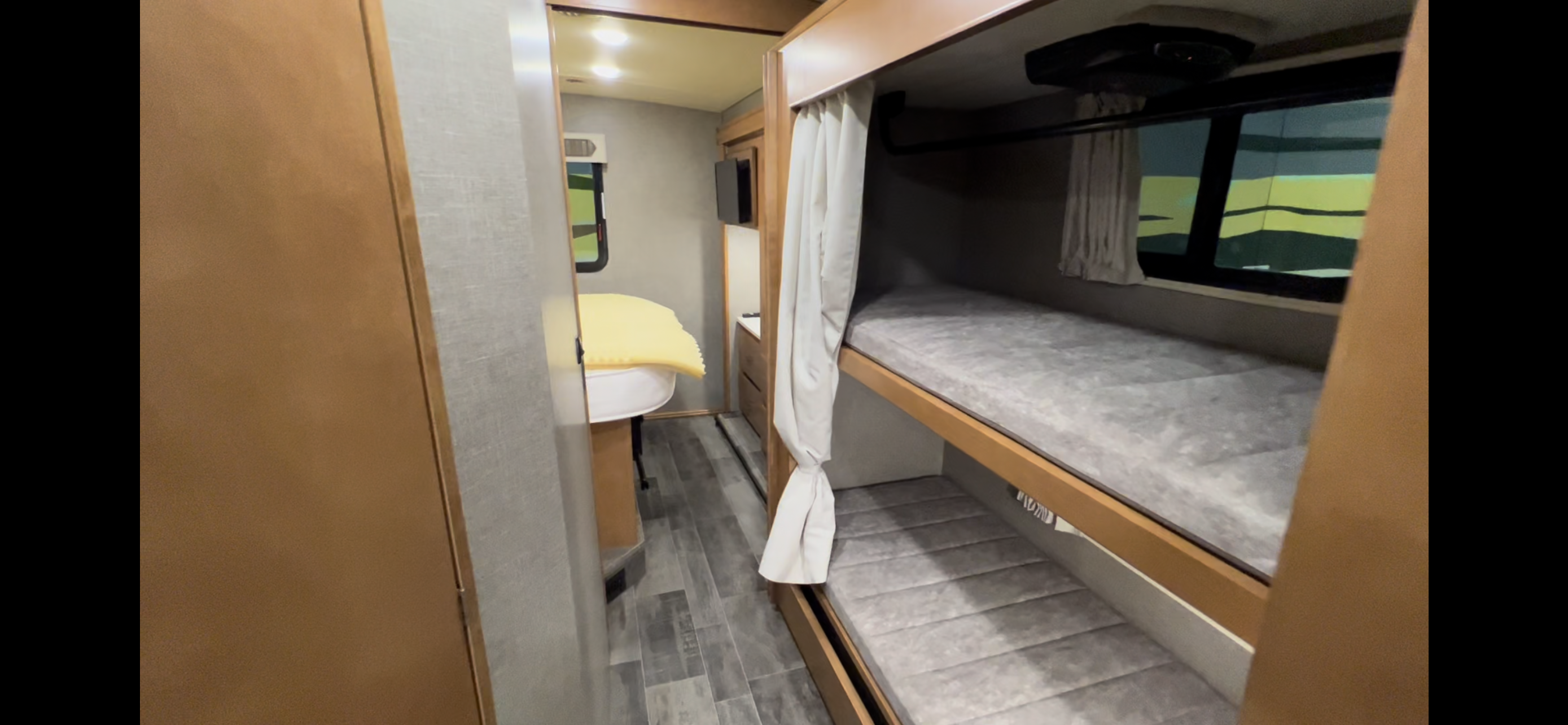 Comfortable RV rental interior with practical bunk beds and privacy curtains, plus a versatile sleeping area further inside.. Winnebago Vista 2019