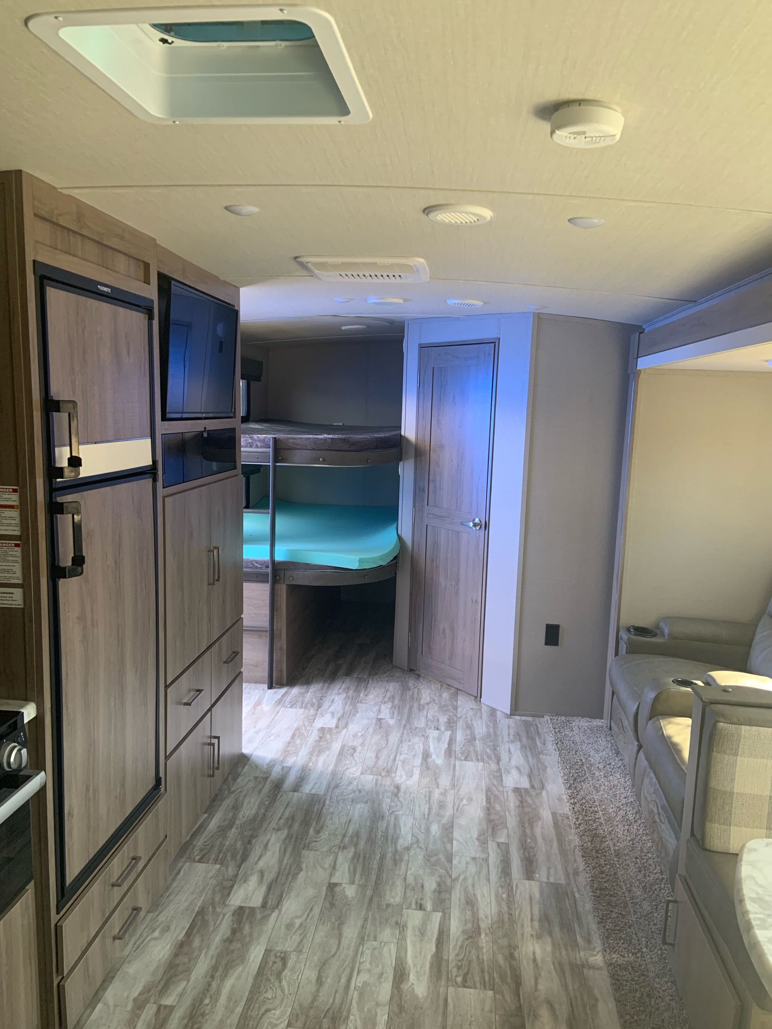 Inside a modern **RV rental**: kitchenette, bunk beds with bright mattresses, and a cozy lounge area.. Grand Design 2800BH 2021