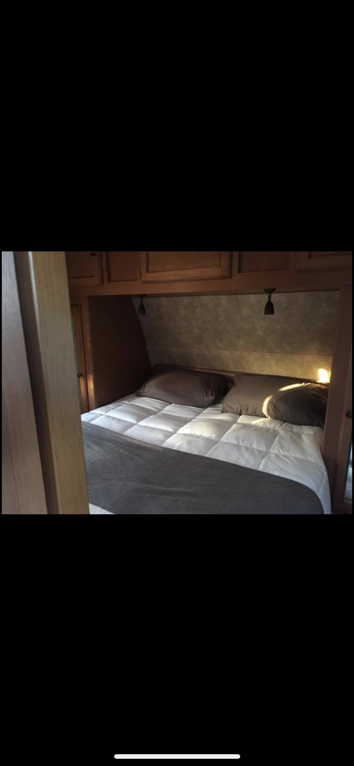 Cozy RV rental bedroom features a neatly made bed with white comforter, brown pillows, and reading lights.. Gulf Stream Ultra-Lite 2014