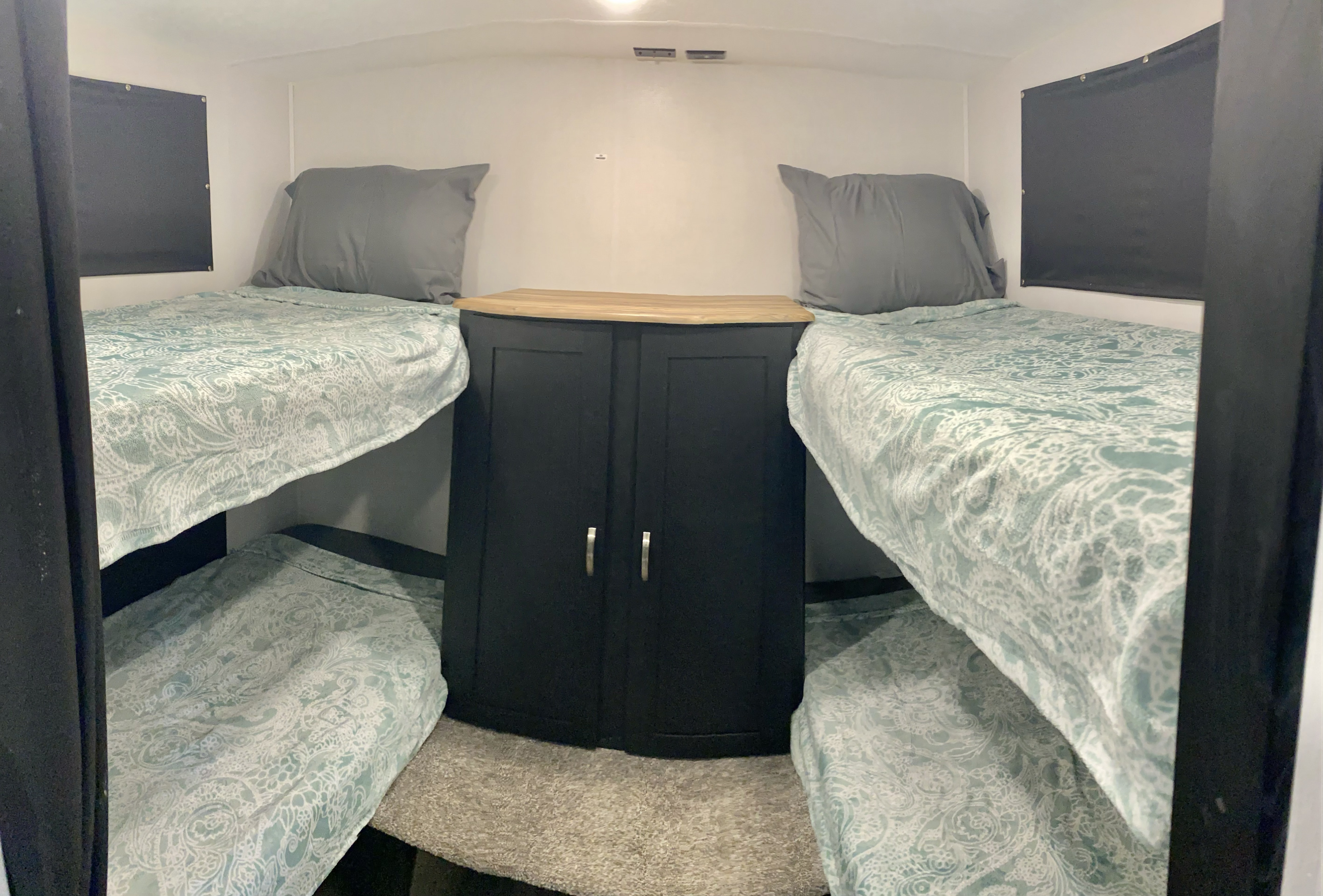 RV rental sleeping space featuring four bunk beds with light blue patterned bedding and a central wood-top cabinet.. Coachmen Freedom express select 2022