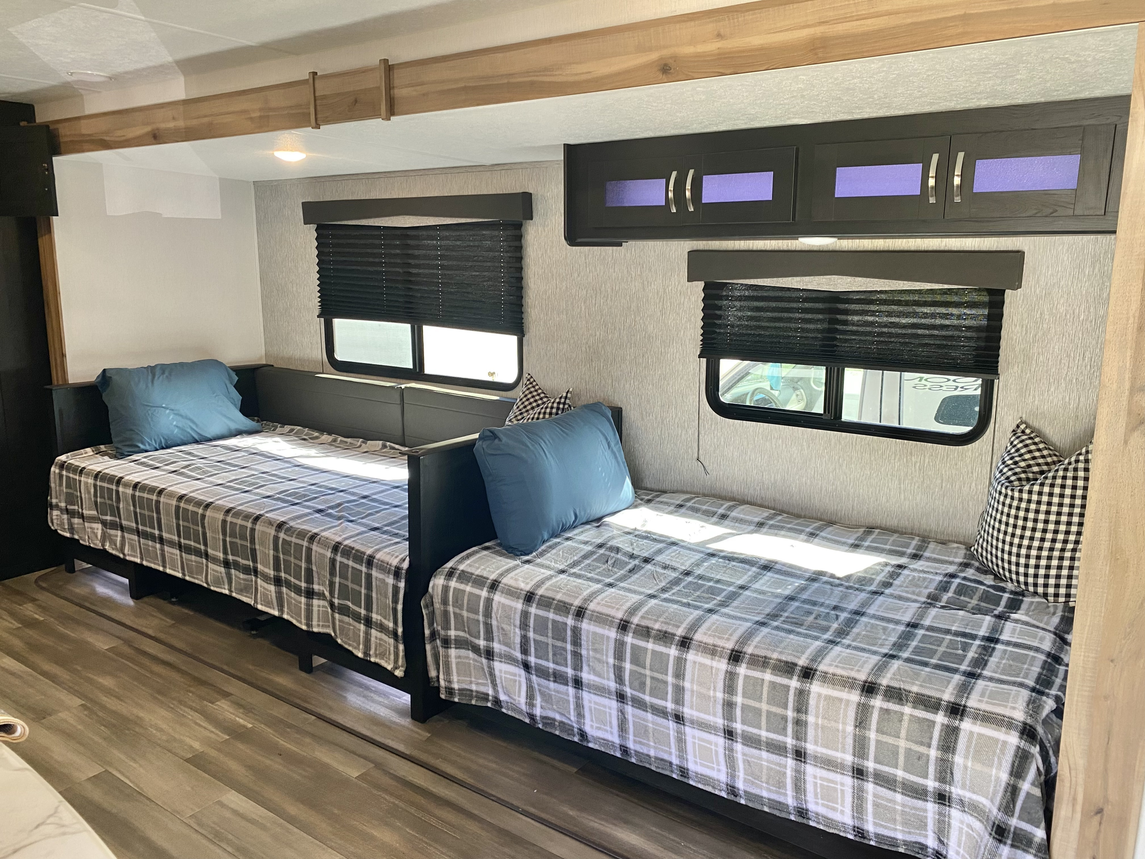 RV rental interior: two cozy bunk beds with plaid blankets, pillows, windows, and modern overhead storage.. Coachmen Freedom express select 2022