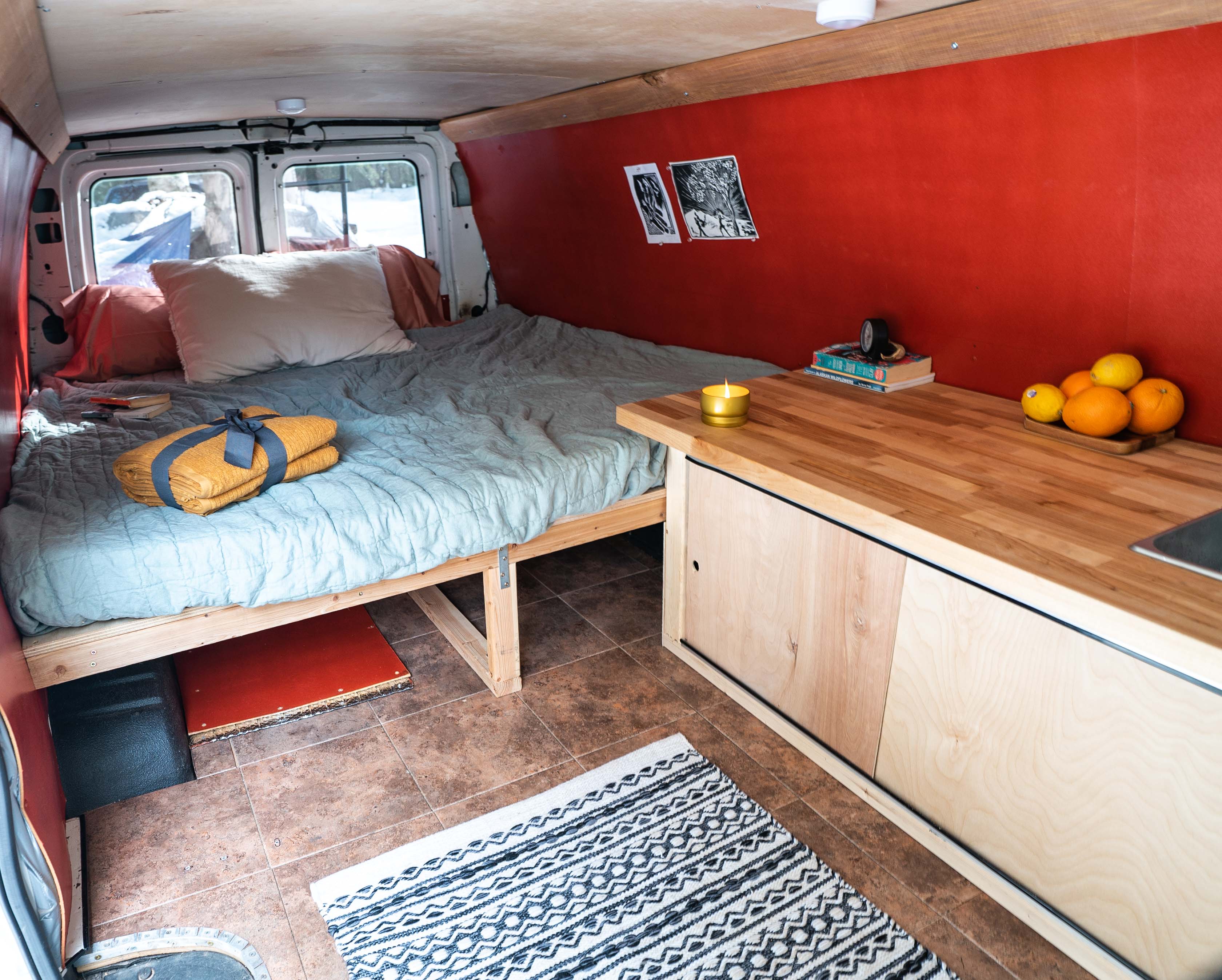 Experience van life in this cozy RV rental! Features a comfy bed, wood kitchenette, and vibrant red interior panels for mobile adventures.. Ford Econoline 2006