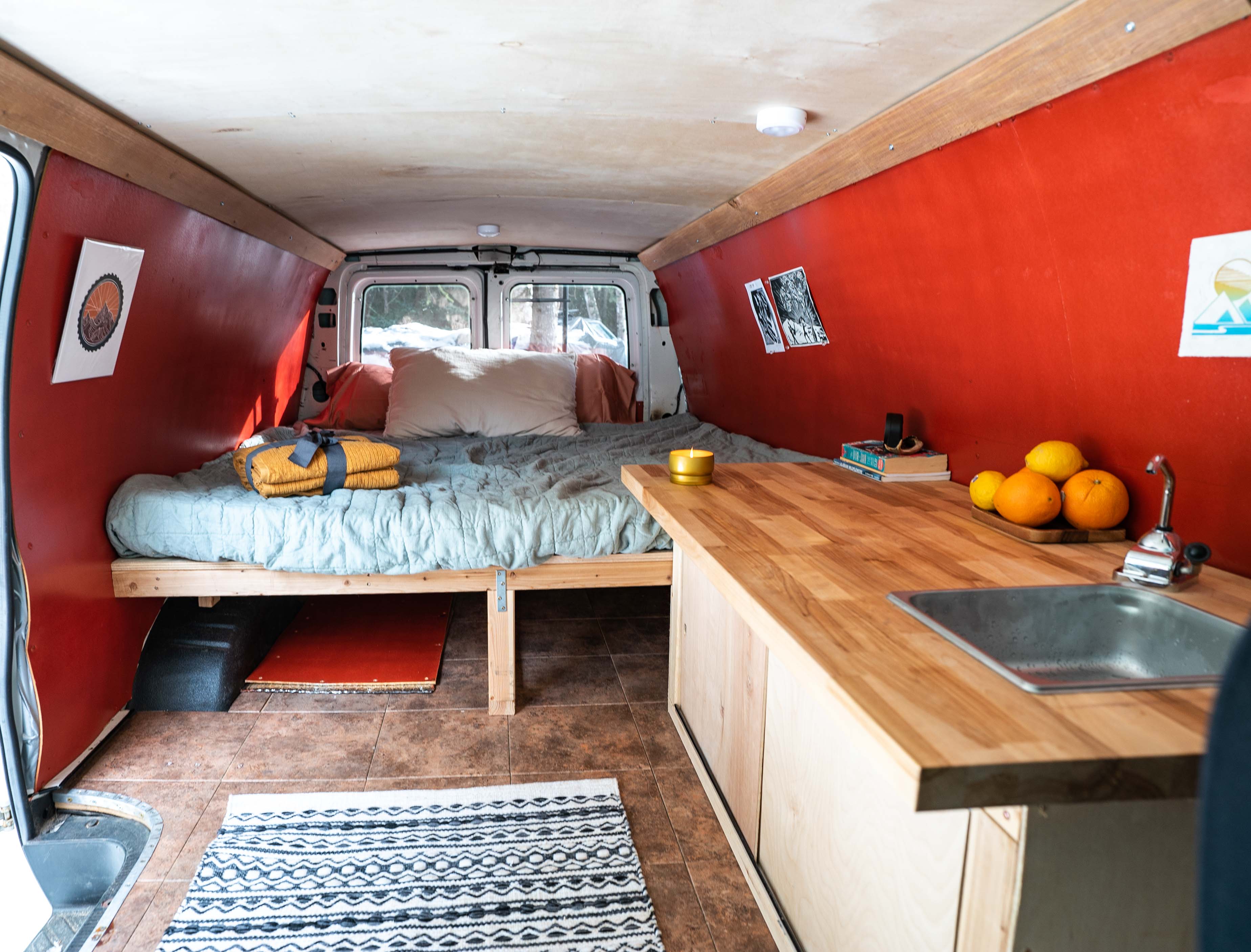 Cozy RV rental interior with a bed, kitchen, and warm lighting, perfect for van life adventures.. Ford Econoline 2006