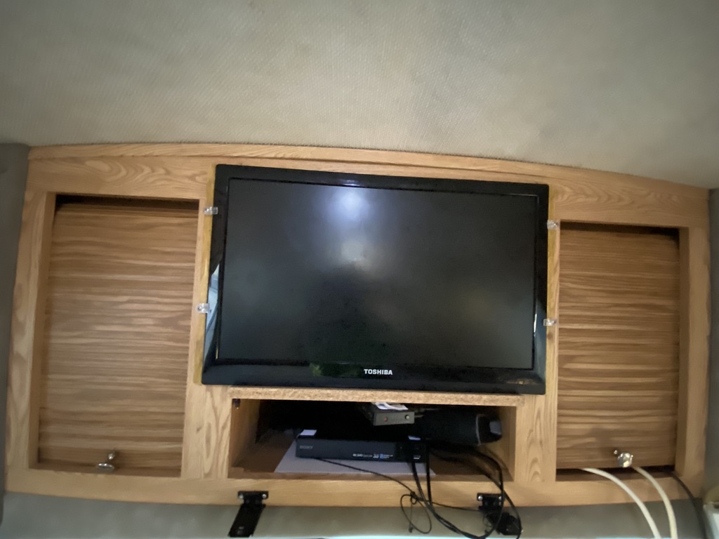 RV rental entertainment setup: Toshiba TV, media devices, and wooden storage cabinets. Enjoy onboard movies & music.. R-Vision Trail-Lite 2001