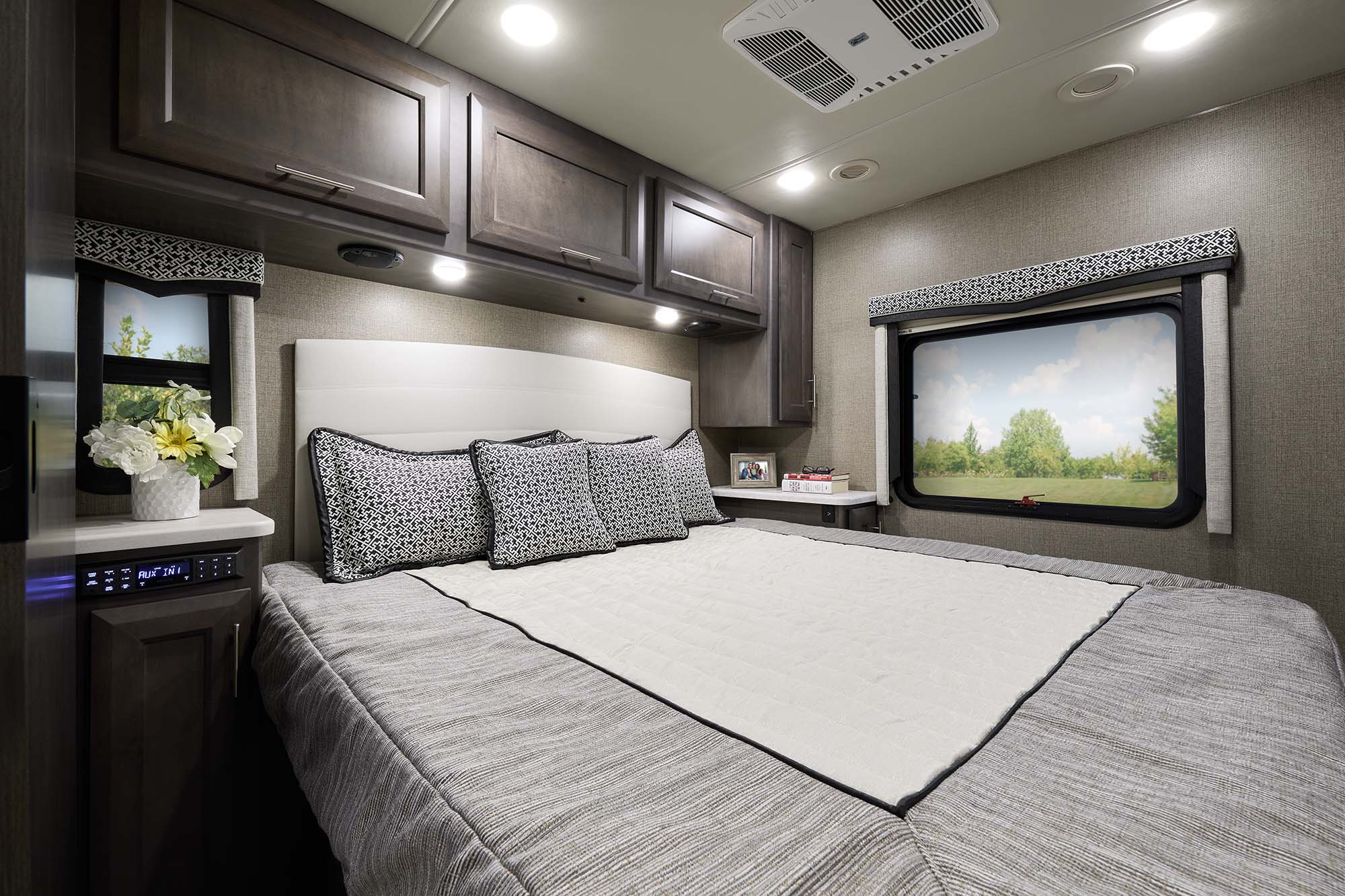 Cozy RV rental bedroom with comfortable bed, overhead storage, and window view. Perfect for your next road trip adventure.. Thor Omni RS36 2022