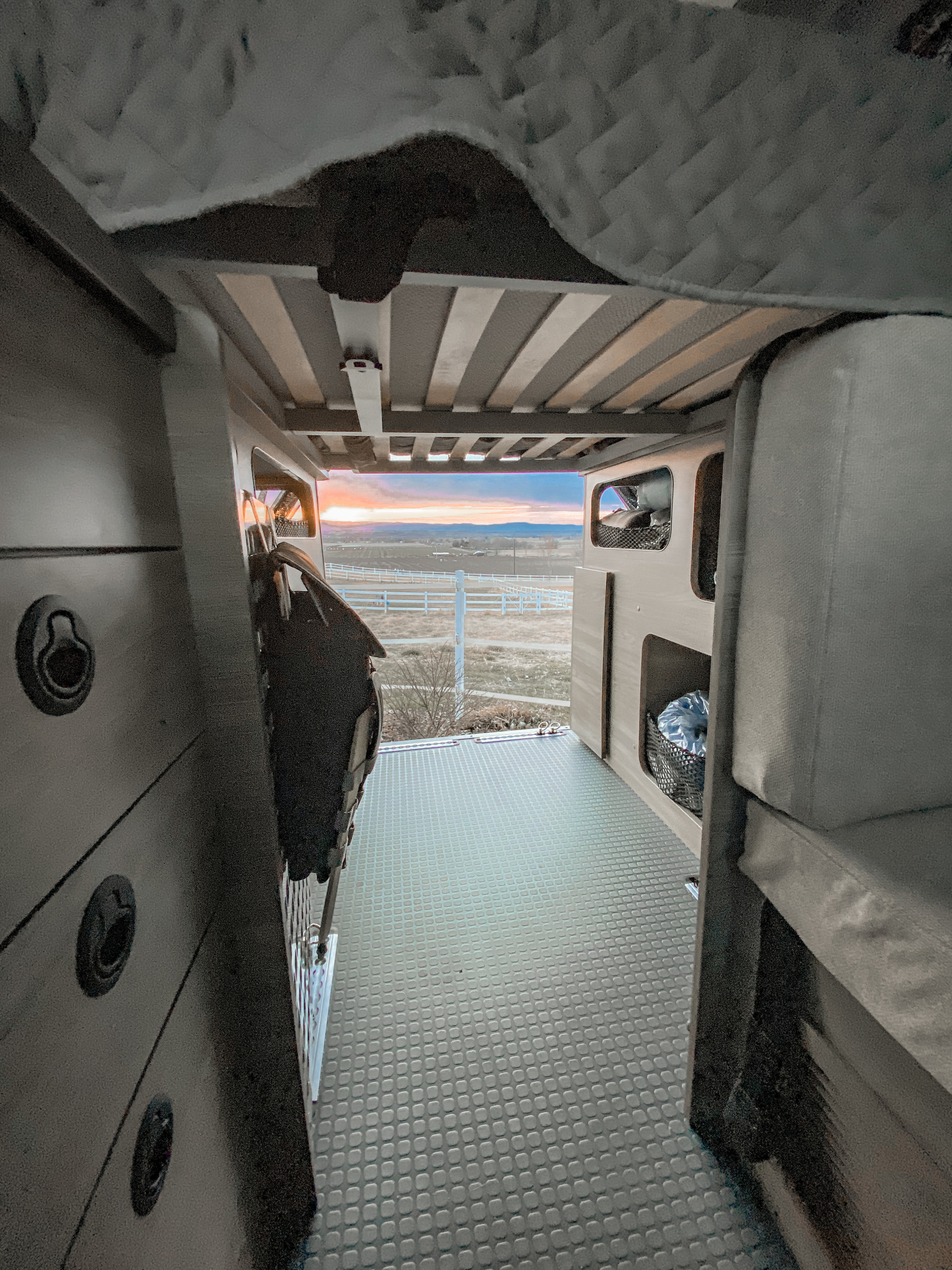 RV rental interior at sunset. View from the back of a spacious camper van with textured flooring & comfortable sleeping areas.. Winnebago Solis Pocket 2022