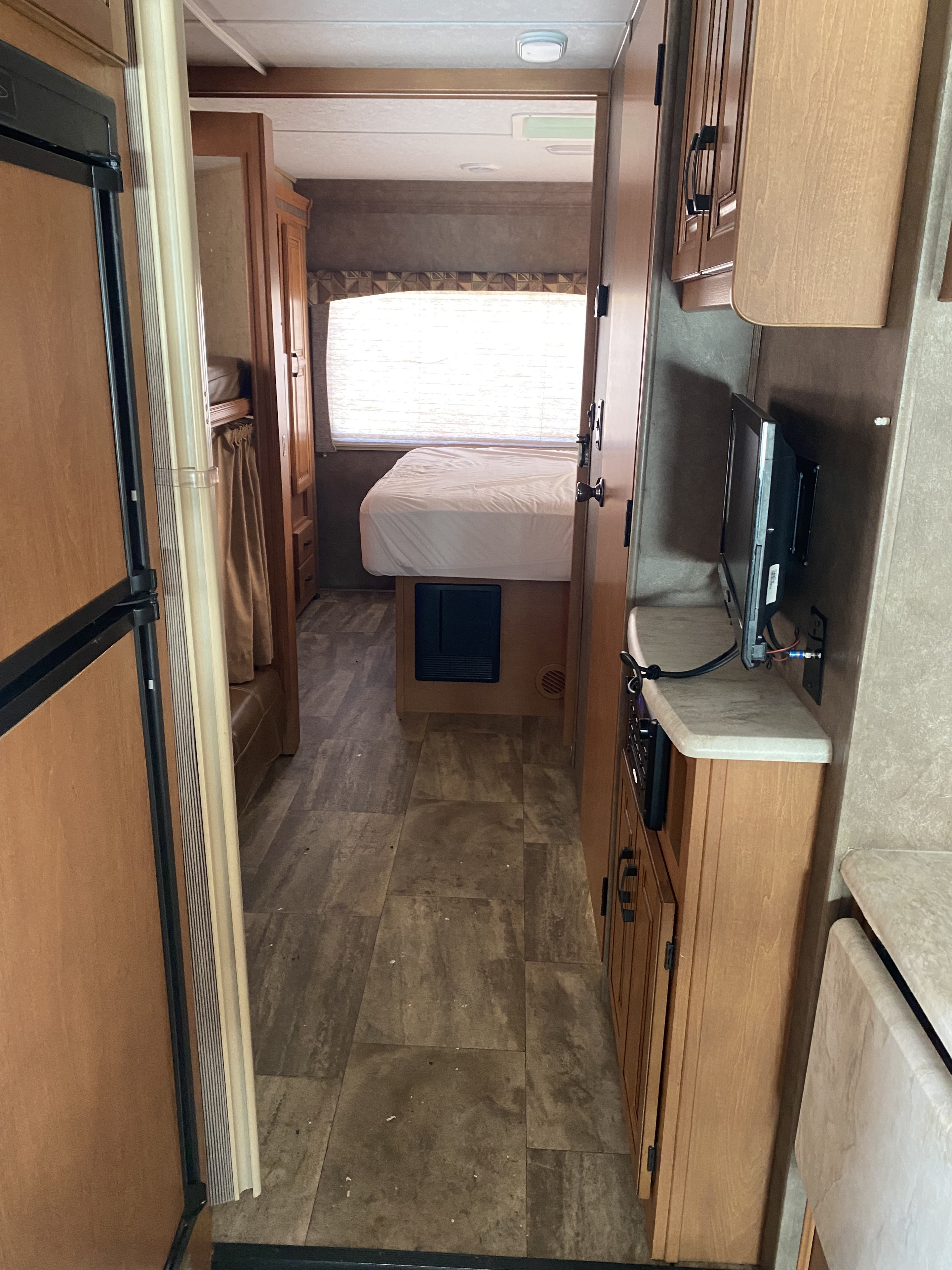 RV rental interior: Hallway view of kitchen, bunks, bedroom, and TV with wood-look flooring.. Forest River Sunseeker 2016