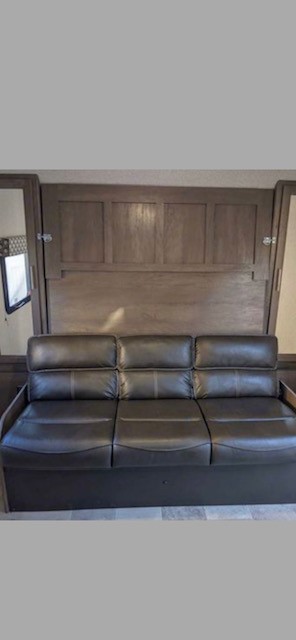 Discover this RV rental's versatile interior: a comfortable black leather trifold sofa that converts to a bed.. Keystone RV Light LX 2125BH 2021
