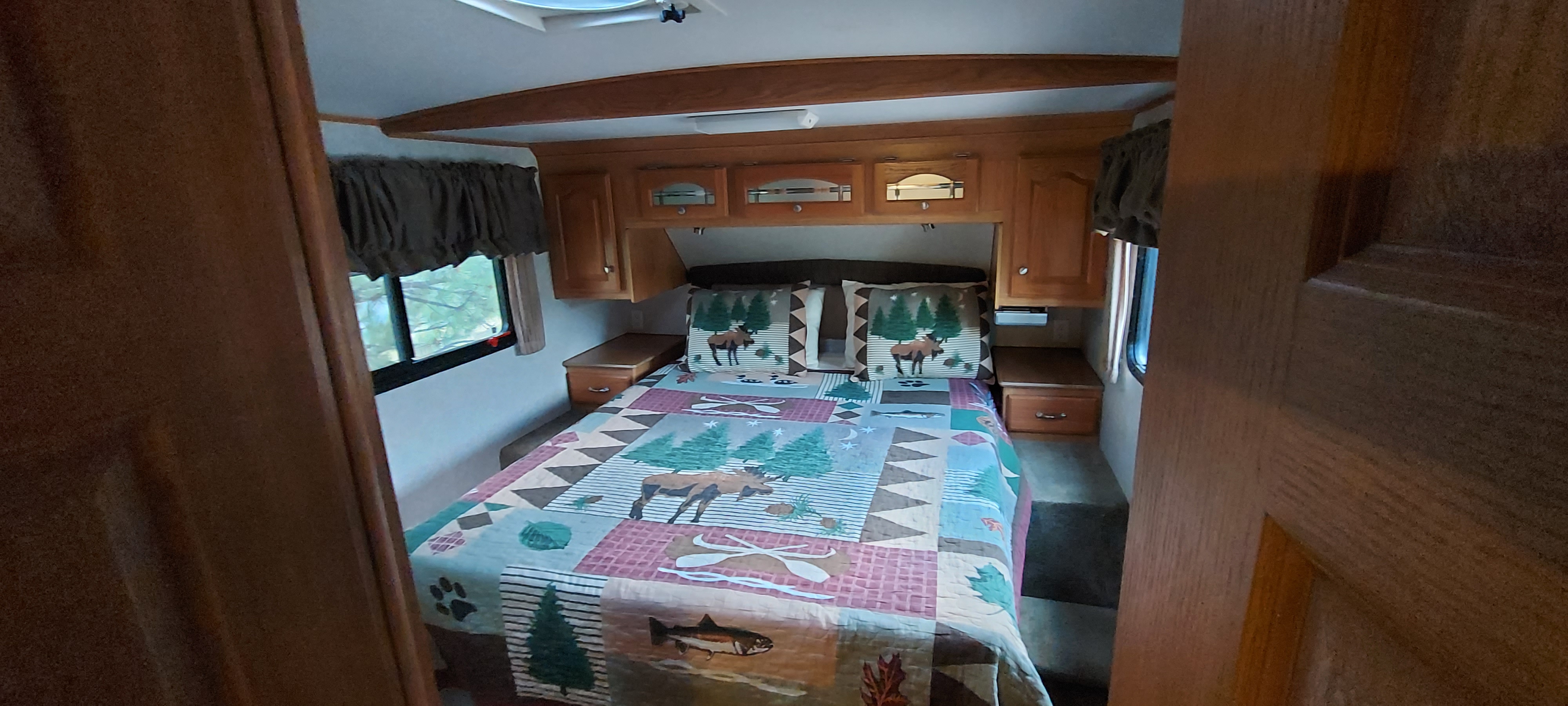 Cozy RV rental bedroom with nature-themed bedding, overhead cabinets, and windows, perfect for your next adventure.. Glendale Titanium 2004
