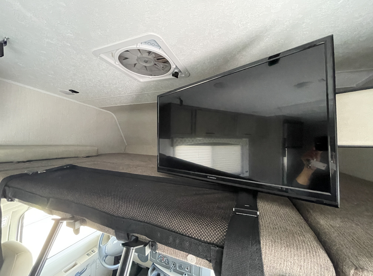 RV rental interior featuring a cabover bunk bed with safety net, wall-mounted TV, and ceiling fan.. Coachmen Freelander 2020