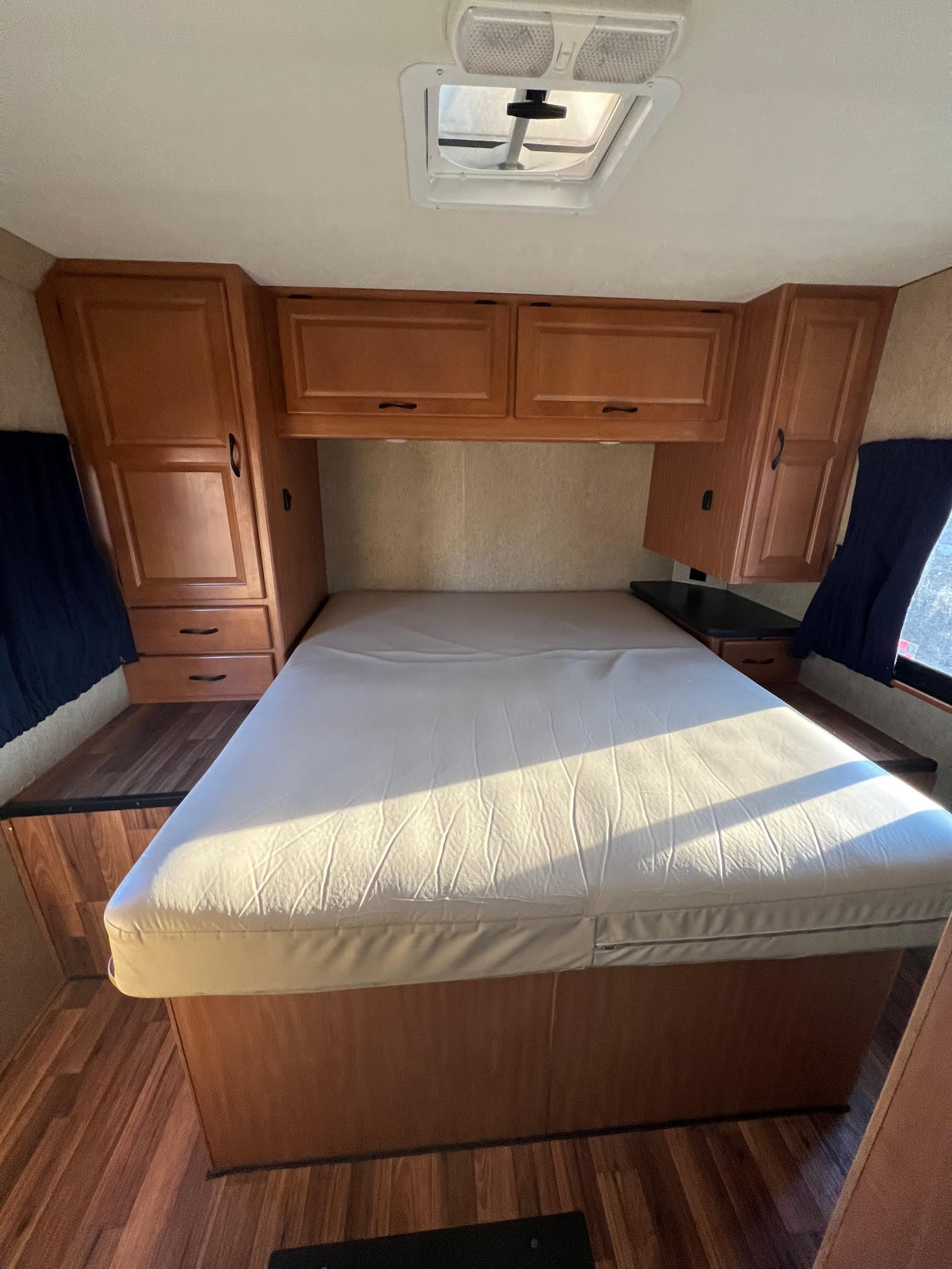 This rv rental bedroom features a large bed, wooden cabinets, and a ceiling skylight, offering a functional interior.. Thor Majestic 2017