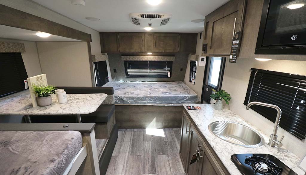 RV rental interior: compact living space with bed, dinette, kitchenette, and bunk, perfect for travel.. KZ Sportmen classic  181bh 2020