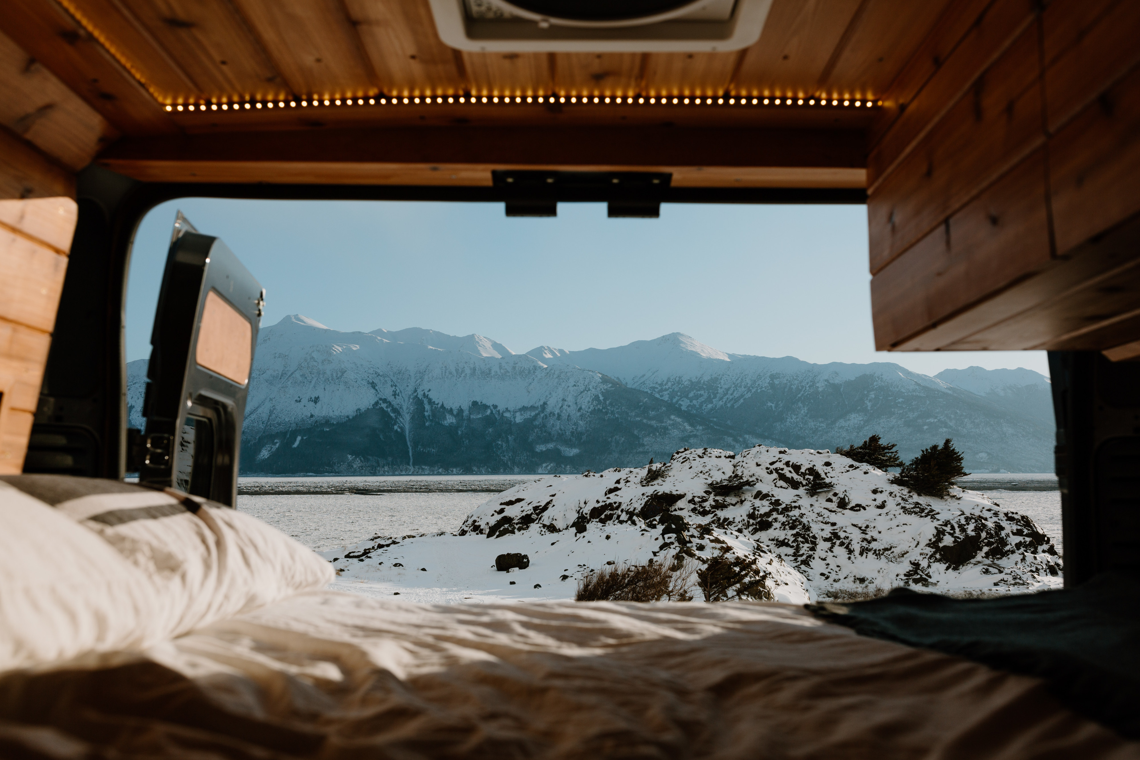Cozy rv rental view: snowy mountains, water, and an open door from inside a van.. Dodge Ram 2500 (Class B) 2022