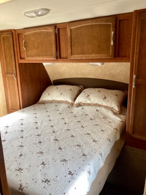 Cozy RV bedroom with a comfortable bed and storage cabinets, ideal for your next RV rental.. Jayco Jay Feather 2011