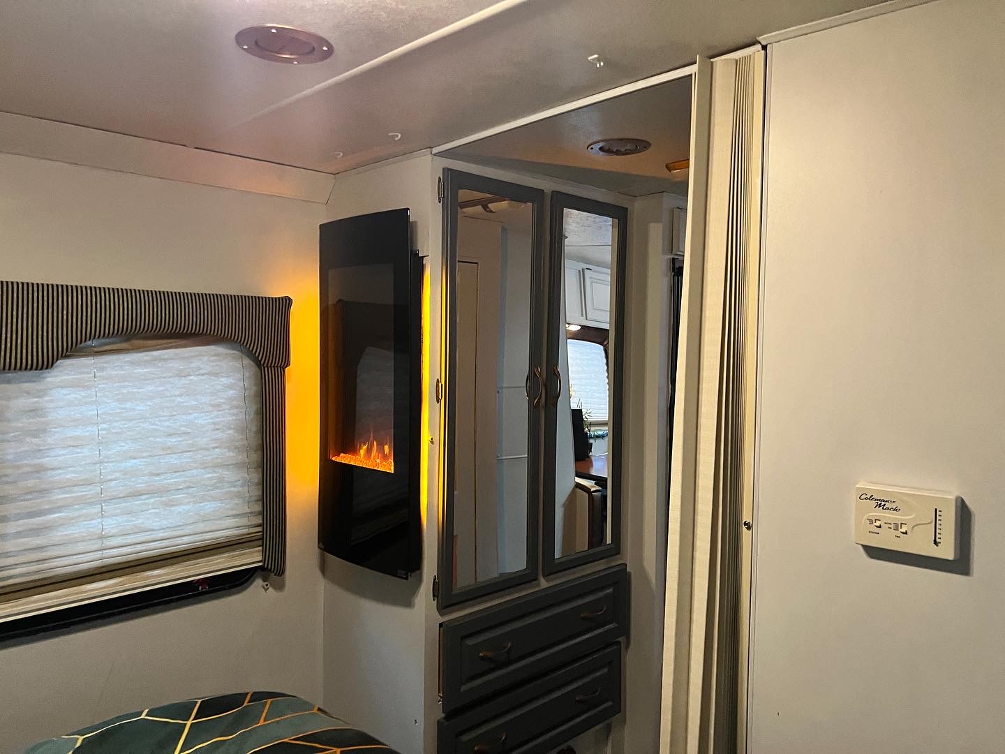 RV rental interior: modern electric fireplace, large window, and mirrored cabinets create a comfy space.. Thor Motor Coach Hurricane 2006