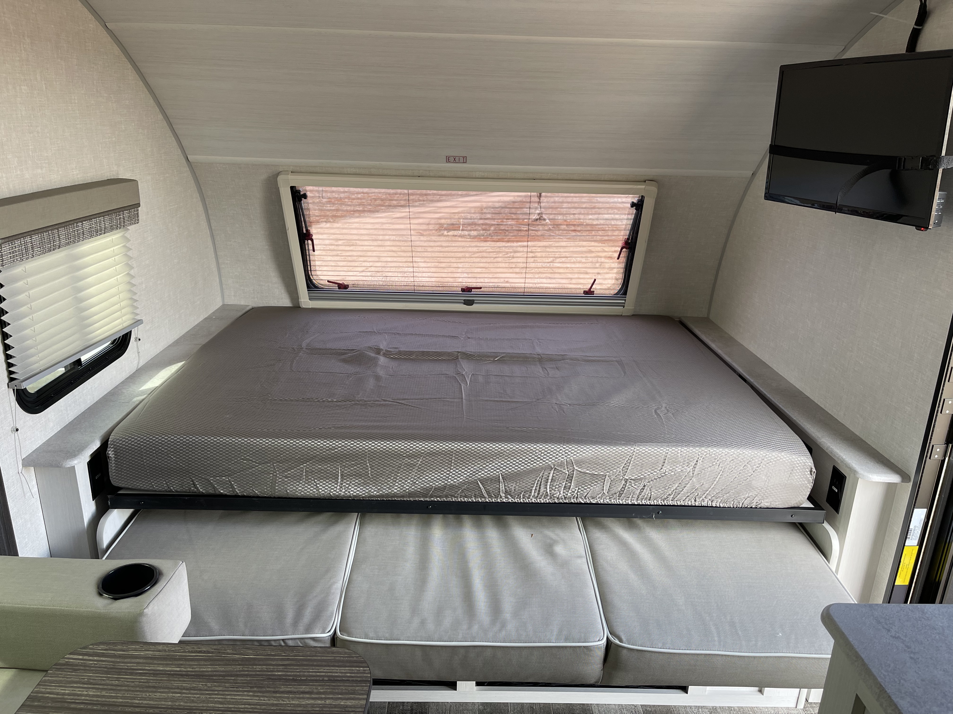 Inside an RV rental: a modern, versatile space with a bed that folds over a cozy dinette. Includes window & TV.. Forest River RPod193 2022