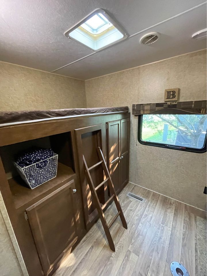 Cozy RV rental interior shows bunk beds, wooden ladder, storage, and skylight. A perfect sleeping space for your next adventure.. Sport Trek Sport Trek Trailer 2015