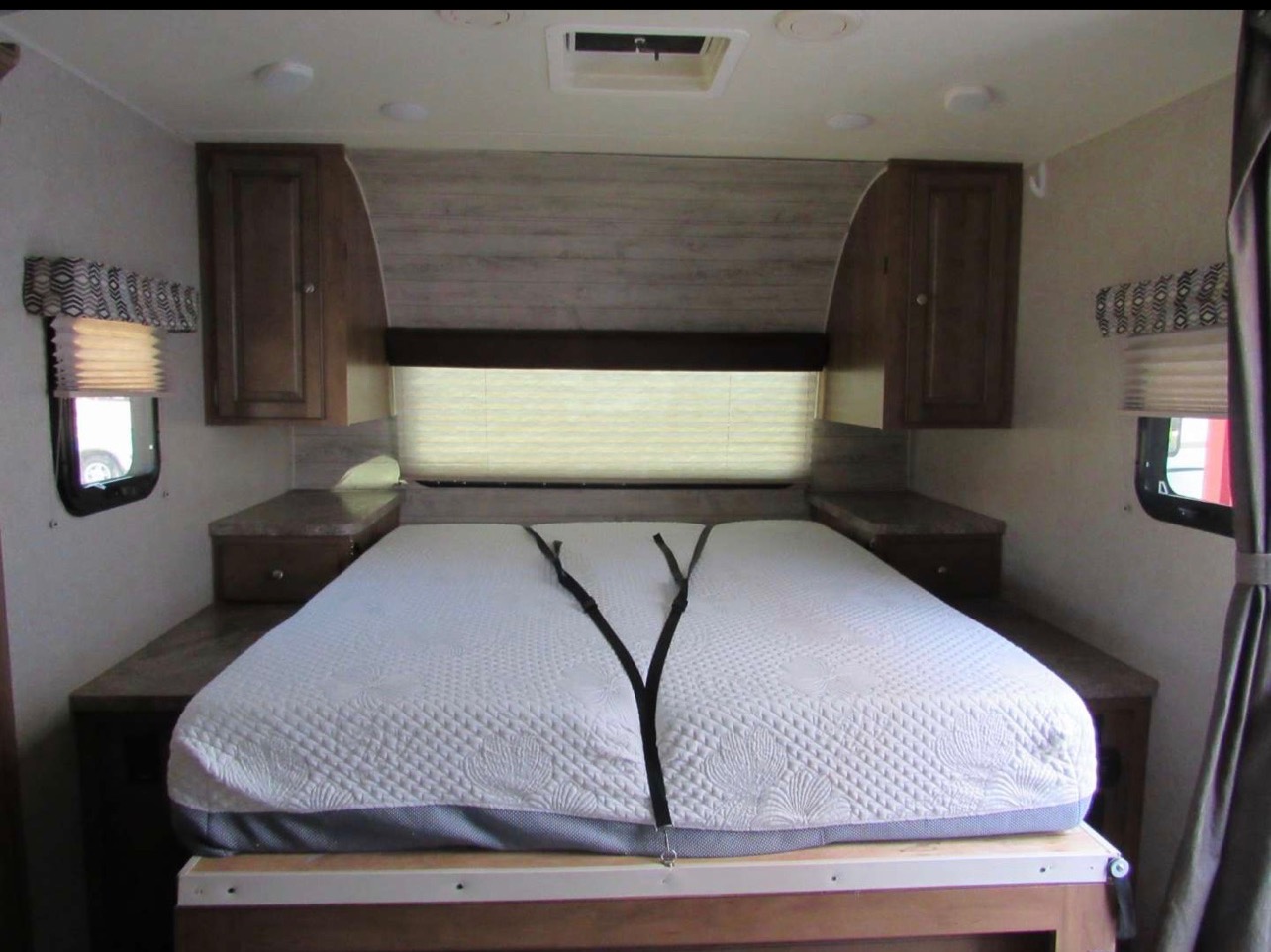 RV rental bedroom: white quilted mattress, built-in side tables, and overhead cabinets with windows. Compact, cozy space.. Forest River Rockwood Mini Lite 2018