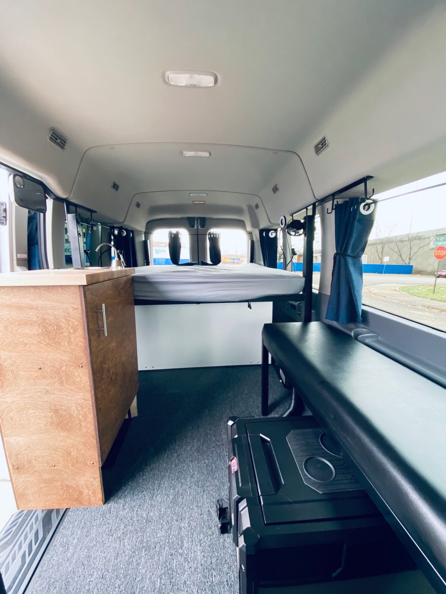 RV rental: Modern camper van interior featuring an elevated bed, kitchen sink, comfy seating, and storage for adventures.. Ford Transit Custom 2019