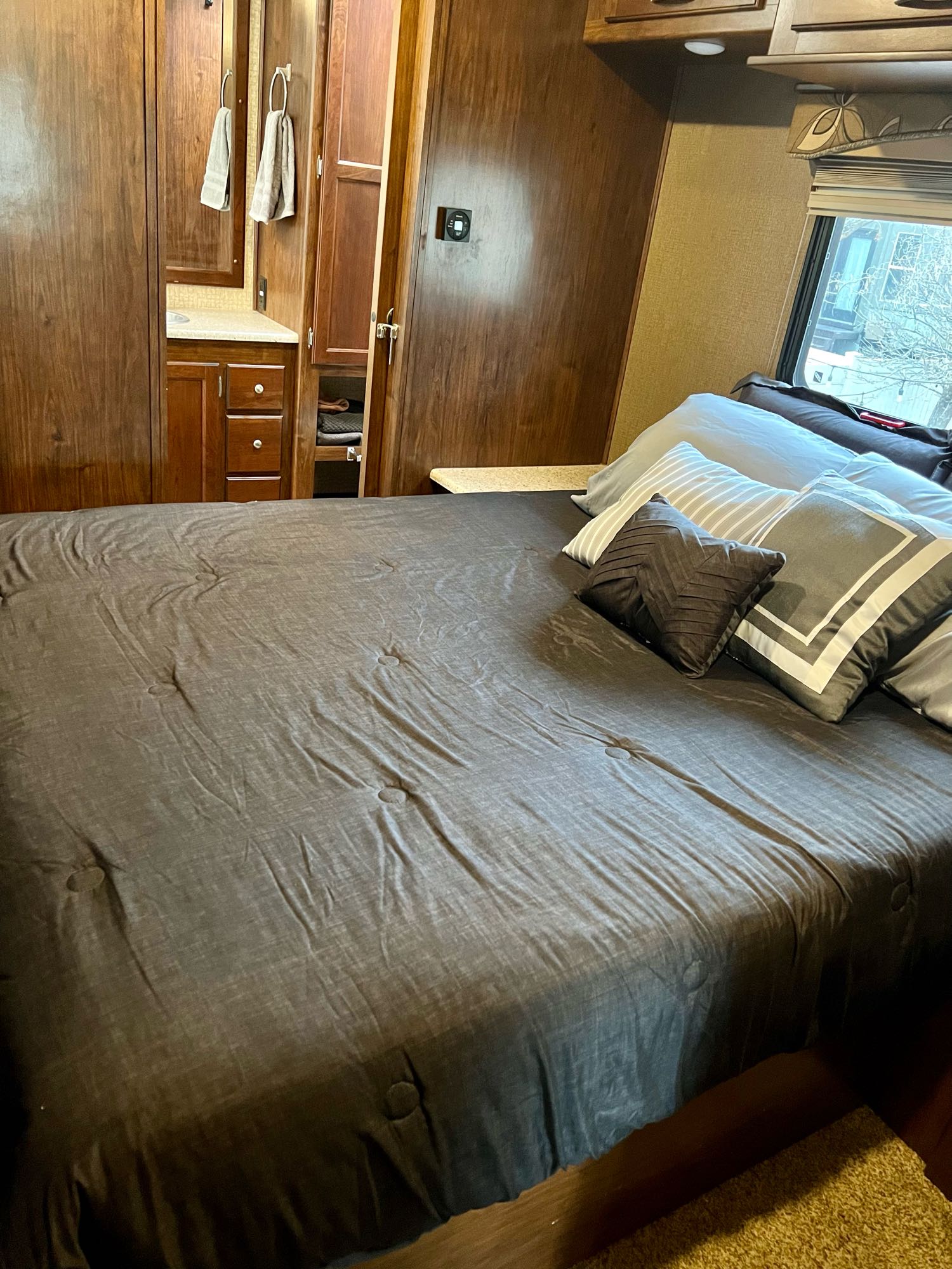 RV rental: A cozy, compact bedroom featuring dark bedding, a built-in wood vanity, and overhead storage.. Forest River Coachmen Mirada 2016