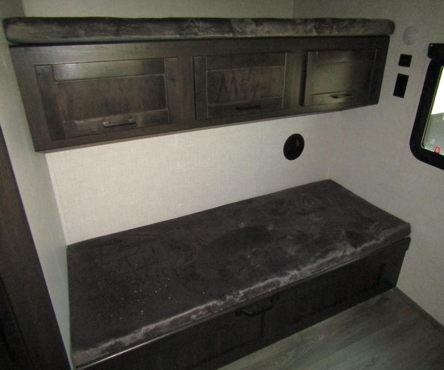 Cozy RV rental interior with dark wood cabinets and a versatile upholstered bench for seating and storage.. keystone cruiser aire-tt 2022